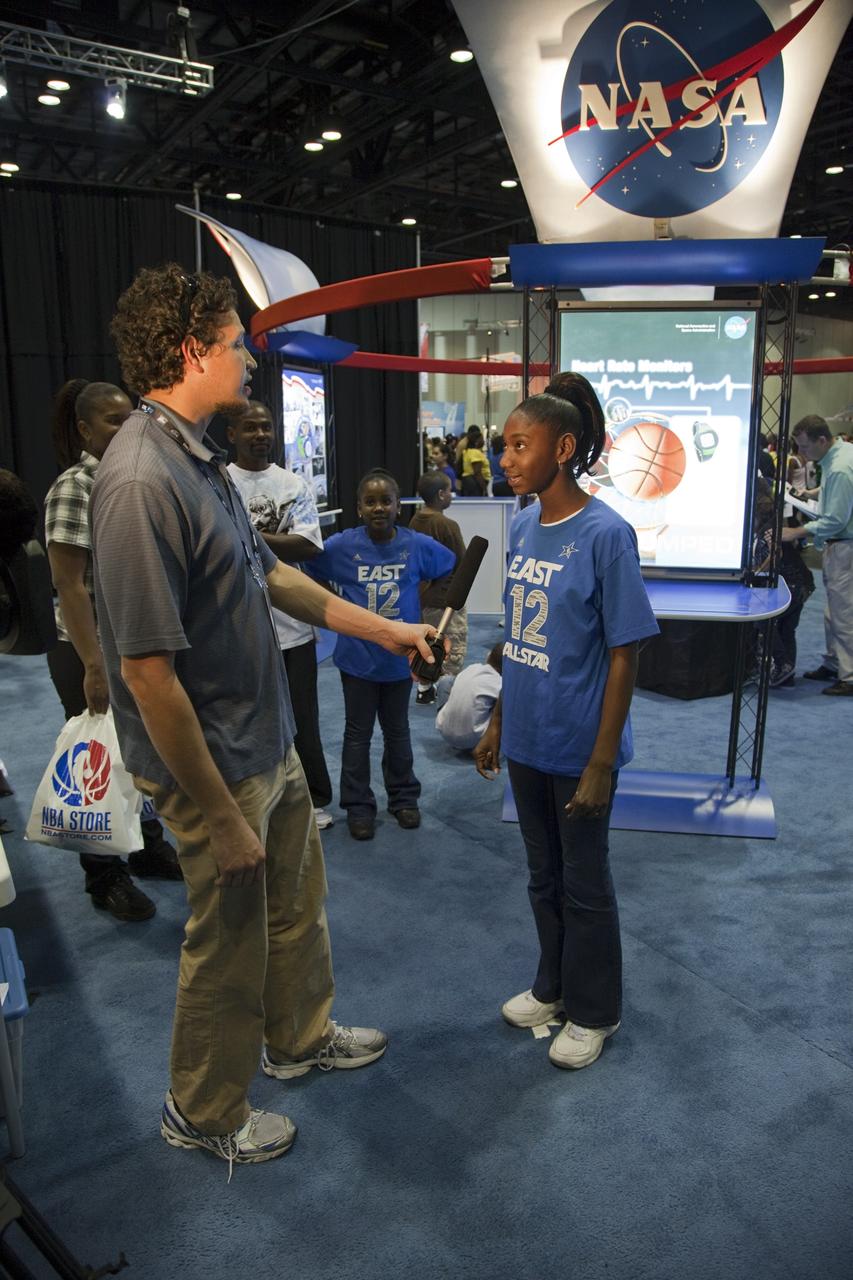 ORLANDO, Fla. -- A representative from NASA's Kennedy Space Center in Florida speaks with a young visitor attending the NBA All-Star Jam Session at the Orange County Convention Center in Orlando, Fla. The NASA exhibit offers hands-on educational activities highlighting some of the contributions the space agency has made to sports, transportation and everyday life.     One of the events leading up to the NBA All-Star game being held in Orlando on Feb. 26, the NBA All-Star Jam Session is a basketball experience intended for all ages, allowing fans to compete against their friends in skills challenges and collect autographs from players and legends. Photo credit: NASA/Frankie Martin