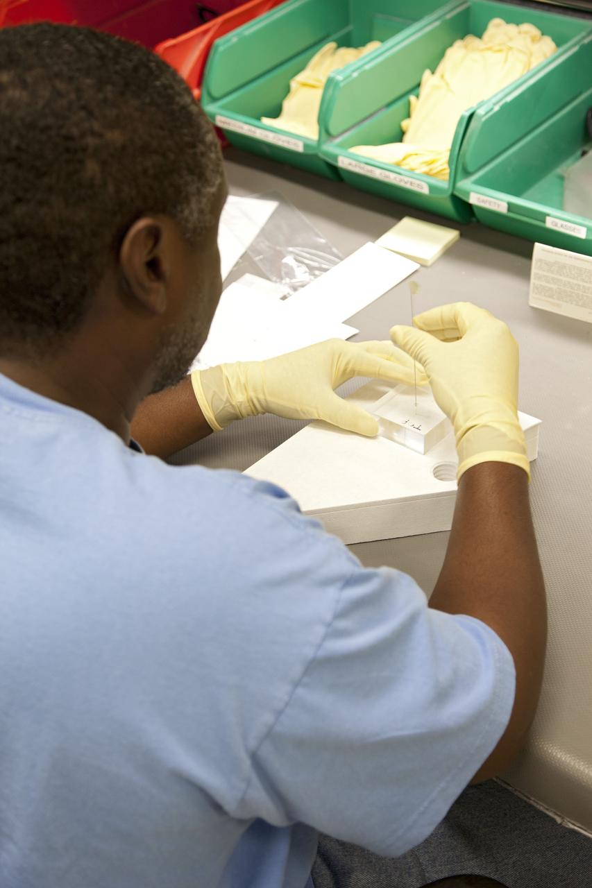 CAPE CANAVERAL, Fla. -- Damon Petty, a United Space Alliance technician at NASA's Kennedy Space Center in Florida, inspects a heat shield tile that will be installed to the backshell of the Orion Multi-Purpose Crew Vehicle's Exploration Flight Test EFT-1 capsule. The work to manufacture and inspect the tiles is taking place in Kennedy's Thermal Protection System Facility. EFT-1 will be used during Orion's first test flight in space. For more information, visit www.nasa.gov/orion. Photo credit: Frankie Martin