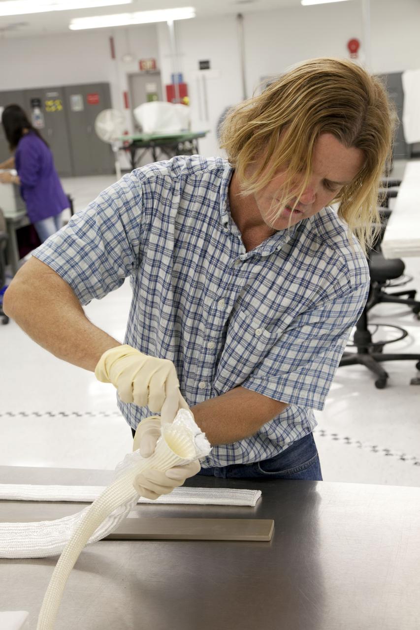 CAPE CANAVERAL, Fla. -- -- Tim Wright, a United Space Alliance engineering manager at NASA's Kennedy Space Center in Florida, explains the properties of the thermal barriers that will be installed to the backshell of the Orion Multi-Purpose Crew Vehicle's Exploration Flight Test EFT-1 capsule. The work to manufacture and inspect the tiles is taking place in Kennedy's Thermal Protection System Facility. EFT-1 will be used during Orion's first test flight in space. For more information, visit www.nasa.gov/orion. Photo credit: Frankie Martin