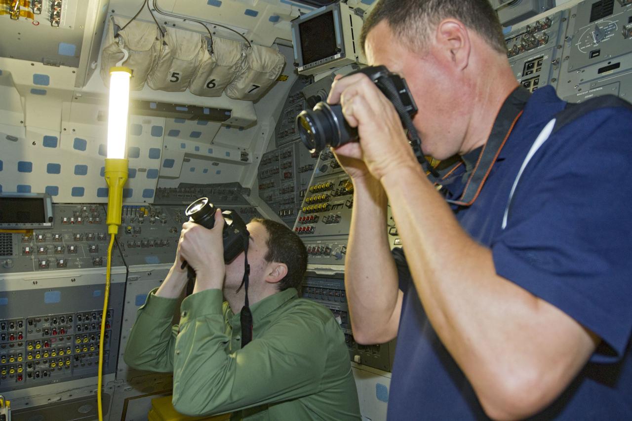 CAPE CANAVERAL, Fla. -- Inside the cramped confines of space shuttle Endeavour's crew module, photographers document the appearance of the flight deck during a media event at NASA's Kennedy Space Center in Florida.    Ongoing transition and retirement activities are preparing the spacecraft for public display at the California Science Center in Los Angeles. Endeavour flew 25 missions during its 19-year career. Photo credit: NASA/Kim Shiflett