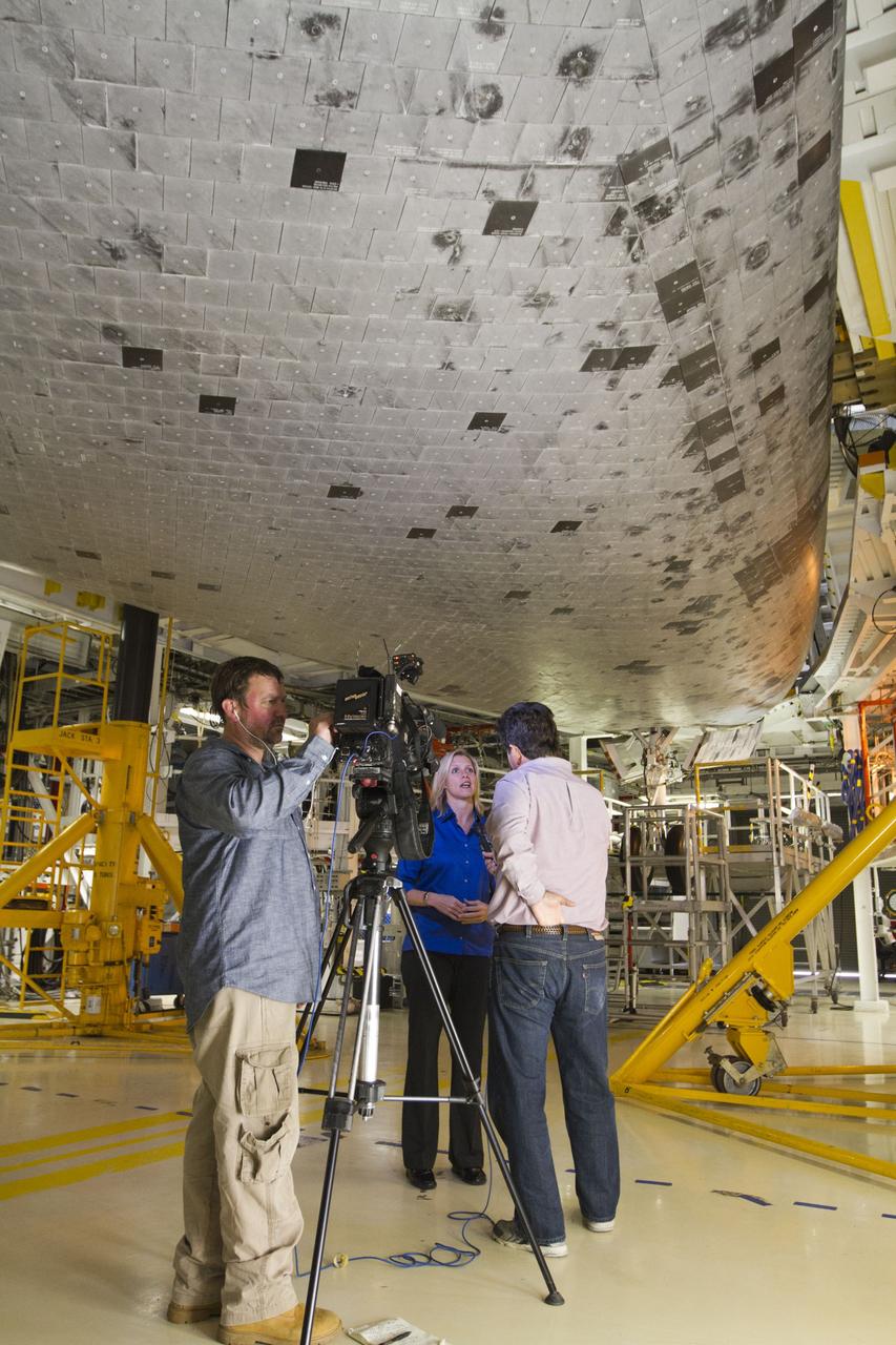 CAPE CANAVERAL, Fla. -- Standing beneath the midbody of space shuttle Endeavour, members of the news media interview Stephanie Stilson, NASA flow director for the shuttles' transition and retirement, inside Orbiter Processing Facility-2 at NASA's Kennedy Space Center in Florida. Stilson was one of several shuttle experts available for interviews around the outside of Endeavour and inside the shuttle's crew compartment.    Ongoing transition and retirement activities are preparing the spacecraft for public display at the California Science Center in Los Angeles. Endeavour flew 25 missions during its 19-year career. Photo credit: NASA/Kim Shiflett