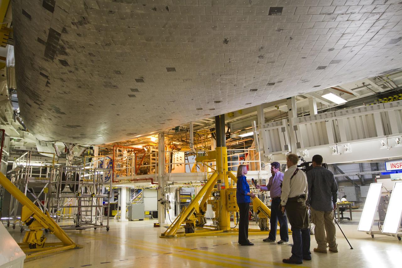 CAPE CANAVERAL, Fla. -- Standing beneath the midbody of space shuttle Endeavour, members of the news media interview Stephanie Stilson, NASA flow director for the shuttles' transition and retirement, inside Orbiter Processing Facility-2 at NASA's Kennedy Space Center in Florida. Stilson was one of several shuttle experts available for interviews around the outside of Endeavour and inside the shuttle's crew compartment.    Ongoing transition and retirement activities are preparing the spacecraft for public display at the California Science Center in Los Angeles. Endeavour flew 25 missions during its 19-year career. Photo credit: NASA/Kim Shiflett