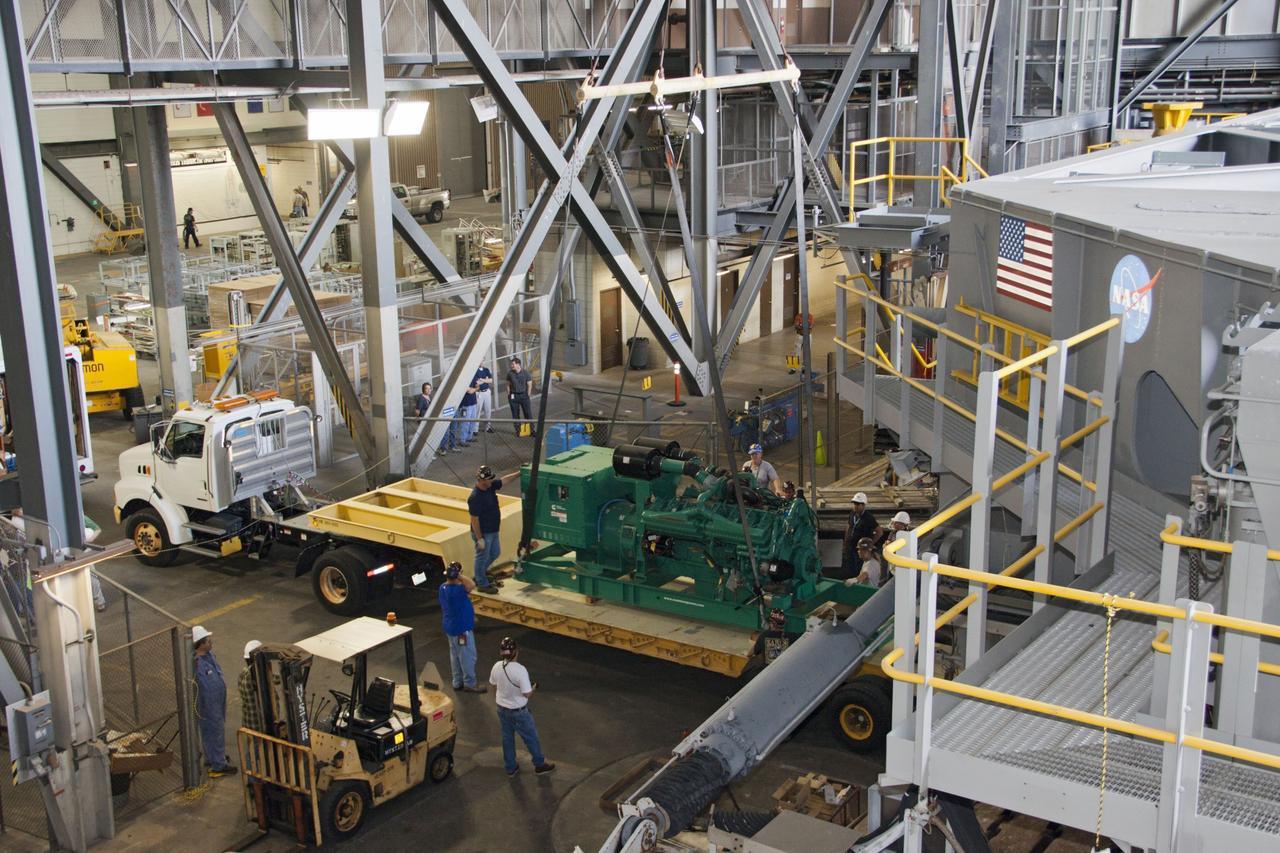 CAPE CANAVERAL, Fla. – Inside the Vehicle Assembly Building at NASA’s Kennedy Space Center in Florida, technicians monitor the progress as a large crane begins to lift a new engine and generator for installation on crawler-transporter 2 CT-2). The Apollo era diesel engines were removed last month. Work continues in high bay 2 to upgrade CT-2 so that it can carry NASA’s Space Launch System heavy-lift rocket, which is under design, and new Orion spacecraft to the launch pad. The crawler-transporters were used to carry the mobile launcher platform and space shuttle to Launch Complex 39 for space shuttle launches for 30 years. Photo credit: NASA/Jim Grossmann