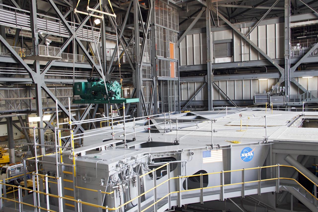 CAPE CANAVERAL, Fla. – Inside the Vehicle Assembly Building at NASA’s Kennedy Space Center in Florida, a large crane is used to lift a new engine and generator high overhead for installation on crawler-transporter 2 CT-2). The Apollo era diesel engines were removed last month. Work continues in high bay 2 to upgrade CT-2 so that it can carry NASA’s Space Launch System heavy-lift rocket, which is under design, and new Orion spacecraft to the launch pad. The crawler-transporters were used to carry the mobile launcher platform and space shuttle to Launch Complex 39 for space shuttle launches for 30 years. Photo credit: NASA/Jim Grossmann
