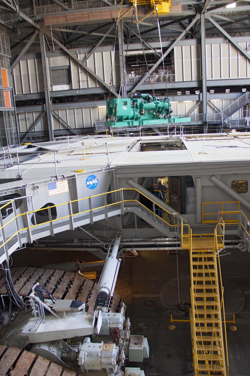 CAPE CANAVERAL, Fla. – Inside the Vehicle Assembly Building at NASA’s Kennedy Space Center in Florida, a large crane lifts a new engine and generator high overhead for installation on crawler-transporter 2 CT-2). The Apollo era diesel engines were removed last month. Work continues in high bay 2 to upgrade CT-2 so that it can carry NASA’s Space Launch System heavy-lift rocket, which is under design, and new Orion spacecraft to the launch pad. The crawler-transporters were used to carry the mobile launcher platform and space shuttle to Launch Complex 39 for space shuttle launches for 30 years. Photo credit: NASA/Jim Grossmann