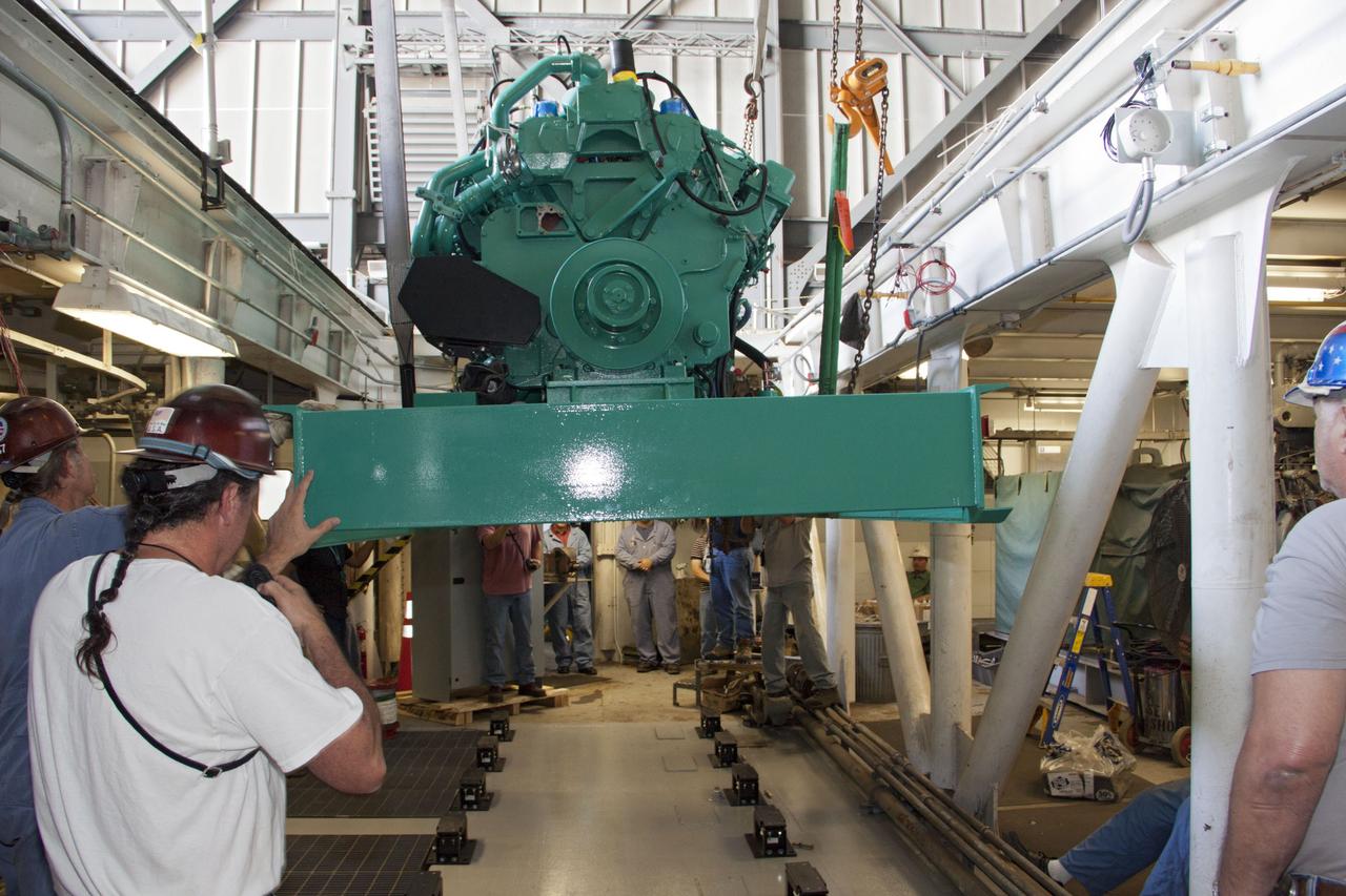 CAPE CANAVERAL, Fla. – Inside the Vehicle Assembly Building at NASA’s Kennedy Space Center in Florida, technicians monitor the progress as a large crane lowers a new engine and generator for installation inside crawler-transporter 2 CT-2). The Apollo era diesel engines were removed last month. Work continues in high bay 2 to upgrade CT-2 so that it can carry NASA’s Space Launch System heavy-lift rocket, which is under design, and new Orion spacecraft to the launch pad. The crawler-transporters were used to carry the mobile launcher platform and space shuttle to Launch Complex 39 for space shuttle launches for 30 years. Photo credit: NASA/Jim Grossmann