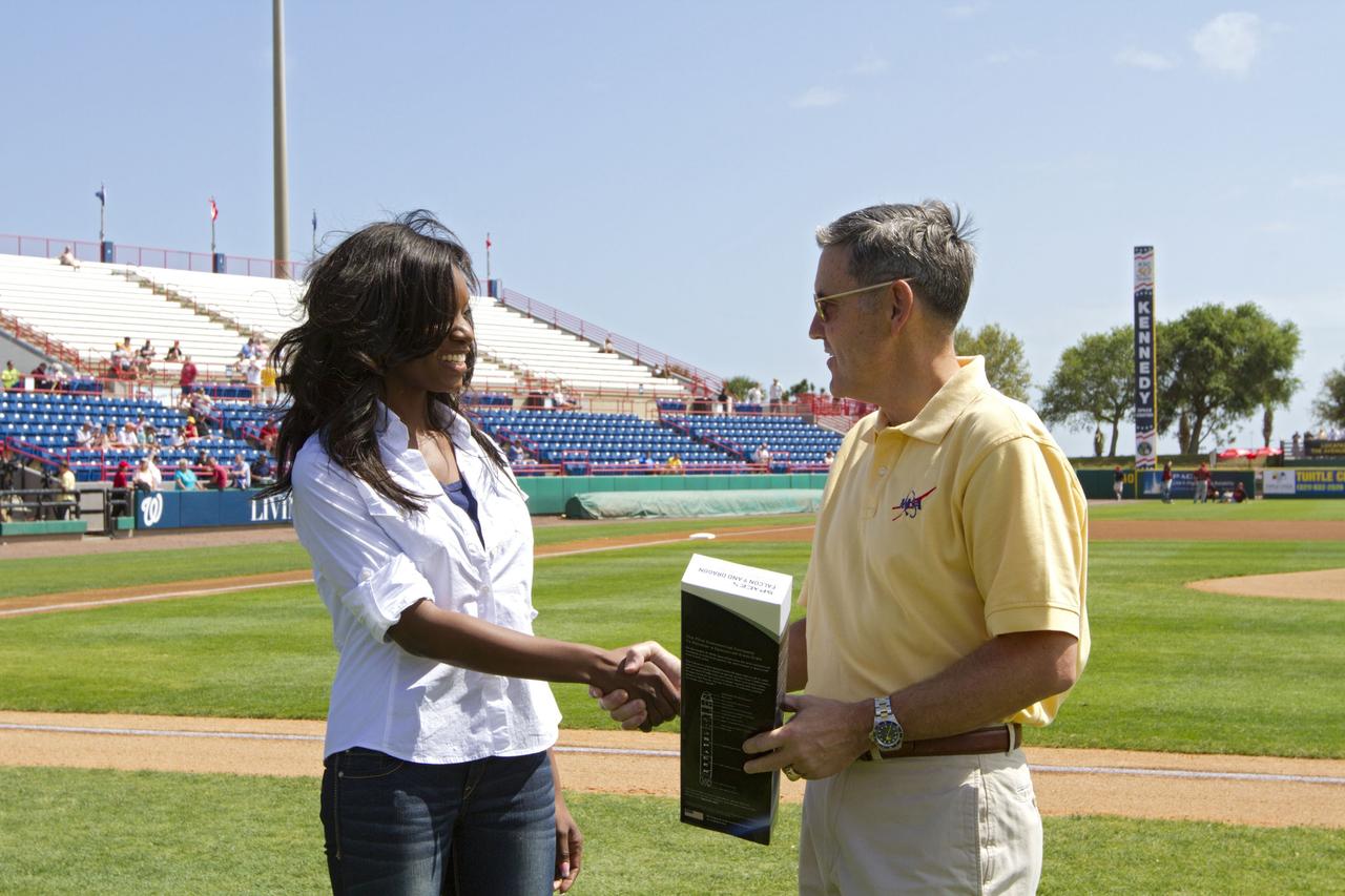 VIERA, Fla. – Space Exploration Technologies’ Christen Brown, left, presents NASA Kennedy Space Center Director Bob Cabana with a model of the company’s Falcon 9 rocket and Dragon spacecraft at the Space Coast Stadium’s Space Day. Known as SpaceX, the company is one of NASA’s commercial partners. Cabana threw the first pitch of a spring training game between Major League Baseball's Washington Nationals and Houston Astros. Kennedy set up a booth at the stadium for the occasion to highlight some of the contributions the space agency has made to sports, transportation and everyday life. A full-scale test version of NASA's new Orion Multi-Purpose Crew Vehicle also was on display outside the stadium to show the public the spacecraft under development that will take astronauts farther into space than ever before. For more information, visit http://www.nasa.gov/kennedy. Photo credit: NASA/Kim Shiflett