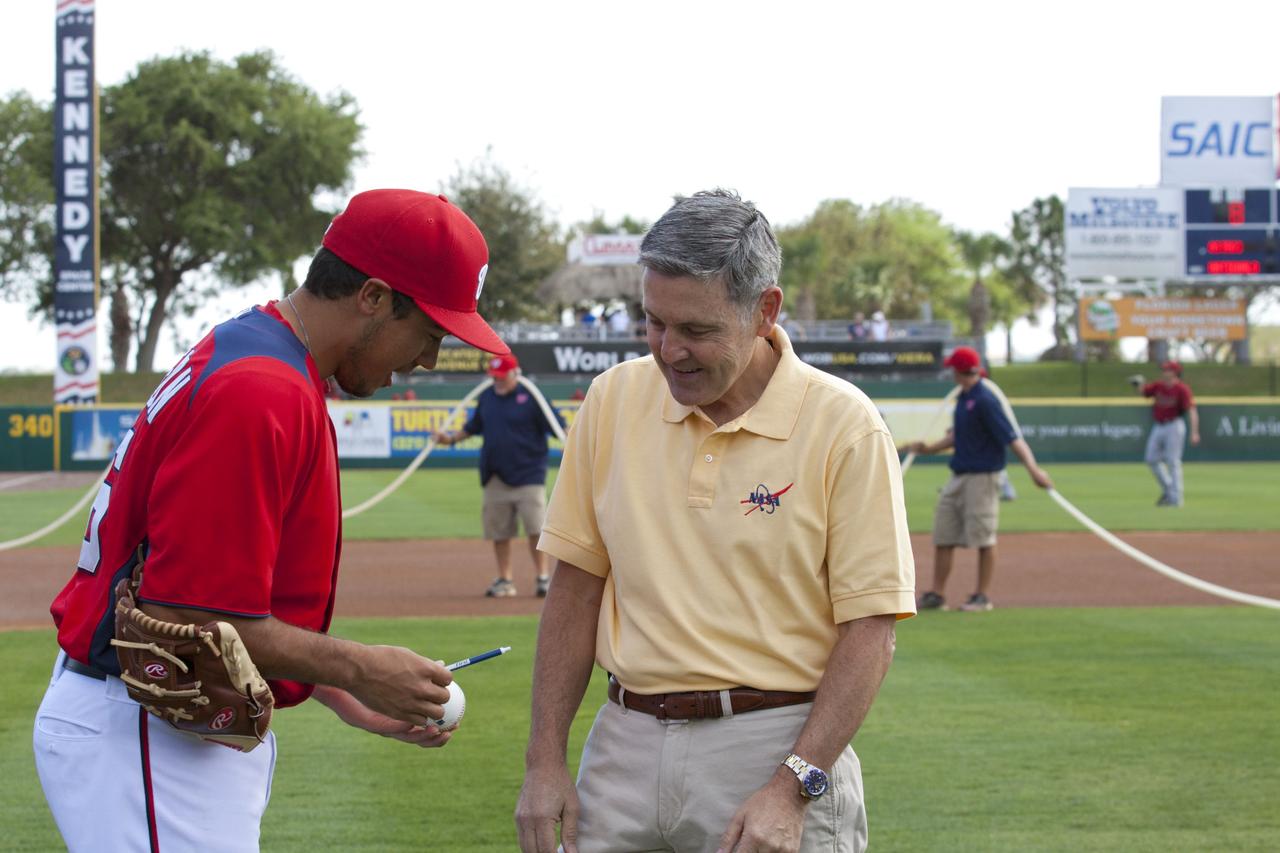 VIERA, Fla. – Third baseman Anthony Rendon, left, of major league baseball’s Washington Nationals offers NASA’s Kennedy Space Center Director Bob Cabana a pen to sign a baseball during a spring training game between the Nationals and the Houston Astros on Space Day at the Space Coast Stadium. Cabana threw the first pitch of the game. Kennedy set up a booth at the stadium for the occasion to highlight some of the contributions the space agency has made to sports, transportation and everyday life. A full-scale test version of NASA's new Orion Multi-Purpose Crew Vehicle also was located outside the stadium to show the public the spacecraft under development that will take astronauts farther into space than ever before. For more information, visit http://www.nasa.gov/kennedy. Photo credit: NASA/Kim Shiflett