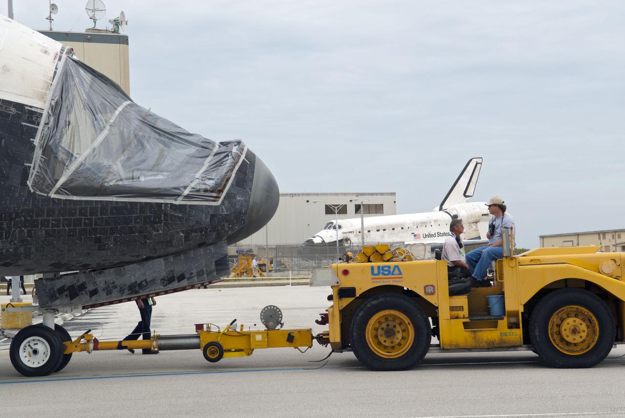 CAPE CANAVERAL, Fla. – At NASA’s Kennedy Space Center in Florida, space shuttle Atlantis is being towed on its way from the Vehicle Assembly Building to Orbiter Processing Facility-1 OPF-1. A view of Atlantis’ nose cone area shows that the forward reaction control system has been removed. In the background is space shuttle Discovery after it was towed out of OPF-1. The work is part of the Space Shuttle Program’s transition and retirement processing of the three space shuttles. Atlantis is being prepared for display at the Kennedy Space Center Visitor Complex and is scheduled to rollover to the complex in November. Photo credit: NASA/Tim Jacobs