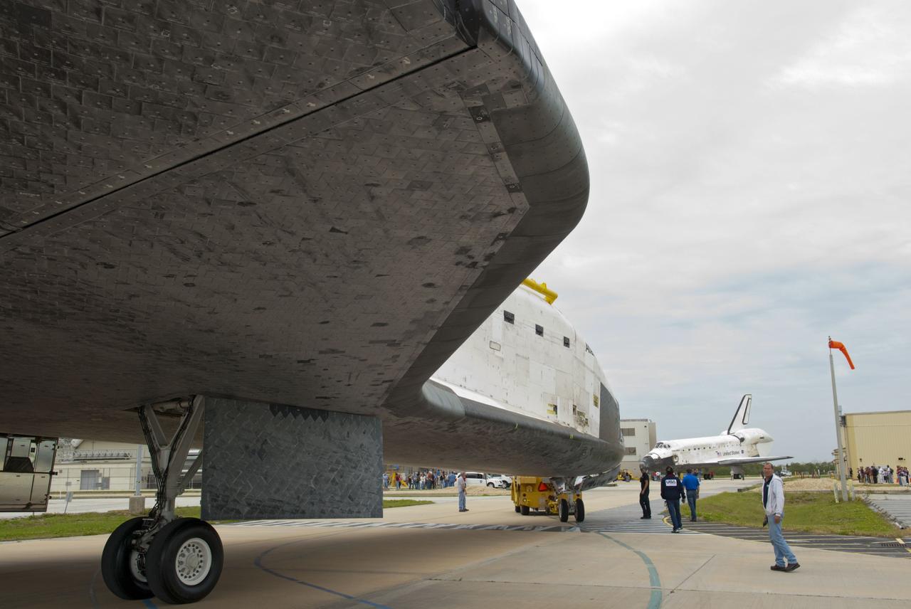 CAPE CANAVERAL, Fla. – At NASA’s Kennedy Space Center in Florida, technicians monitor space shuttle Atlantis as it is towed from the Vehicle Assembly Building toward Orbiter Processing Facility-1 OPF-1. In the background is space shuttle Discovery after it was towed out of OPF-1.      The work is part of the Space Shuttle Program’s transition and retirement processing of the three space shuttles. Atlantis is being prepared for display at the Kennedy Space Center Visitor Complex and is scheduled to rollover to the complex in November. Photo credit: NASA/Tim Jacobs