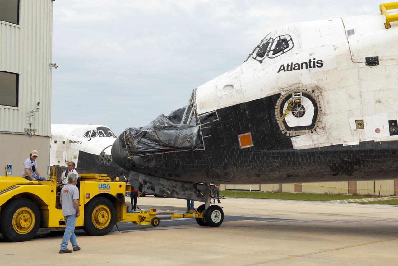 CAPE CANAVERAL, Fla. – At NASA’s Kennedy Space Center in Florida, space shuttle Atlantis is towed toward Orbiter Processing Facility-1 OPF-1 from the Vehicle Assembly Building VAB. In the background, space shuttle Discovery waits for its move to the VAB after being towed out of OPF-1. The work is part of the Space Shuttle Program’s transition and retirement processing of the three space shuttles. Atlantis is being prepared for display at the Kennedy Space Center Visitor Complex and is scheduled to rollover to the complex in November. Photo credit: NASA/Tim Jacobs