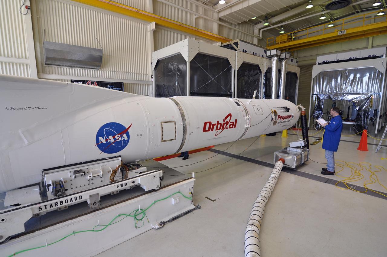 VANDENBERG AIR FORCE BASE, Calif. – In Orbital Science’s hangar at Vandenberg Air Force Base in California, an Orbital technician consults documentation to ensure that all steps in the transfer of an Pegasus XL rocket onto the transporter are properly executed.  The rocket is mated to NASA's Nuclear Spectroscopic Telescope Array, or NuSTAR, telescope, encapsulated in the Pegasus payload fairing.  Cool, dry air is being pumped into the fairing through a purge line to maintain the proper environment for the spacecraft in the confined space.     The transporter will move them to the runway ramp where they will be attached to the underside of Orbital’s L-1011 carrier aircraft. The aircraft will fly the pair from Vandenberg to the Ronald Reagan Ballistic Missile Defense Test Site on the Pacific Ocean’s Kwajalein Atoll for launch. A revised launch date will be set at the Flight Readiness Review, planned for later this week. The high-energy X-ray telescope will conduct a census of black holes, map radioactive material in young supernovae remnants, and study the origins of cosmic rays and the extreme physics around collapsed stars. For more information, visit http://www.nasa.gov/nustar.  Photo credit: NASA/Randy Beaudoin, VAFB