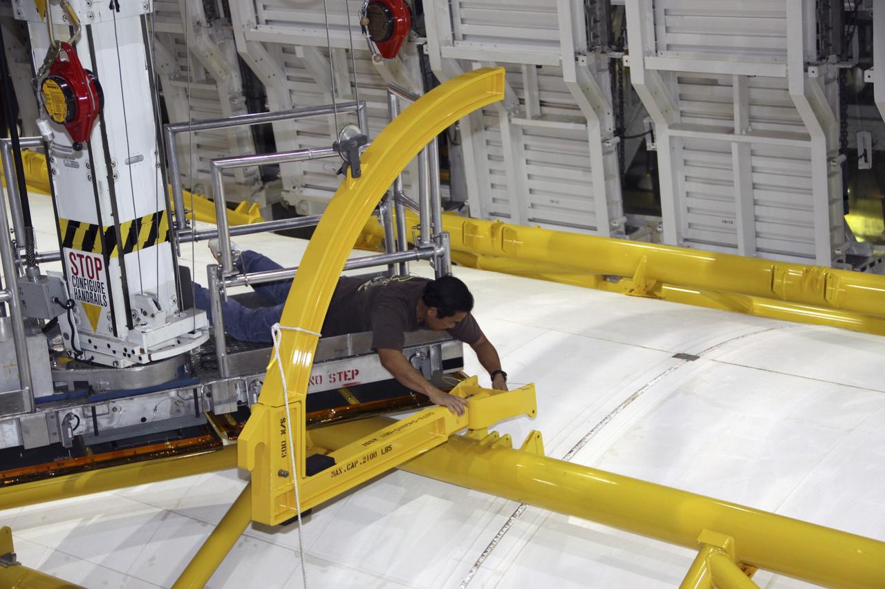 CAPE CANAVERAL, Fla. – In Orbiter Processing Facility-1 at NASA’s Kennedy Space Center in Florida, a United Space Alliance technician attaches a yellow strongback to one of space shuttle Atlantis’ payload bay doors. Strongbacks are used to support and operate the doors when the shuttle is not in space. The work is part of the Space Shuttle Program’s transition and retirement processing of shuttle Atlantis. A groundbreaking was held Jan. 18 for Atlantis' future home -- a 65,000-square-foot exhibit hall in Shuttle Plaza at the Kennedy Space Center Visitor Complex. For more information, visit http://www.nasa.gov/shuttle. Photo credit: NASA/Jim Grossmann