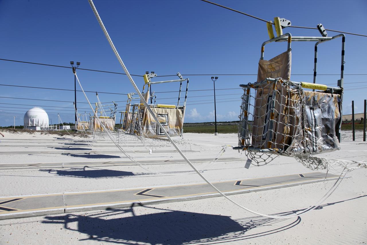 CAPE CANAVERAL, Fla. – At Launch Pad 39A at NASA’s Kennedy Space Center in Florida, the seven slidewire baskets have traveled down the wires to the ground after technicians released them from the 195-foot level for the final time. The baskets will be removed and put in storage.    The system of seven slidewire baskets at launch pads A and B provided an escape route for personnel inside the orbiter or on the orbiter access arm. The baskets are suspended from slidewires that extend from the pad’s Fixed Service Structure to a landing zone 1,200 feet to the west. Each basket could hold up to three people. A braking system catch net and drag chain slowed and then halted the baskets sliding down the wire approximately 55 miles per hour in about half a minute. Photo credit: NASA/Frankie Martin
