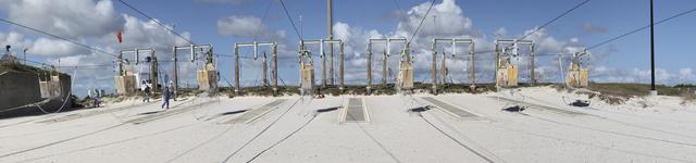CAPE CANAVERAL, Fla. – A panoramic view of the seven slidewire baskets on the ground near Launch Pad 39A at NASA’s Kennedy Space Center in Florida, is seen here after technicians released them from the 195-foot level for the final time. The baskets will be removed and put in storage.    The system of seven slidewire baskets at launch pads A and B provided an escape route for personnel inside the orbiter or on the orbiter access arm. The baskets are suspended from slidewires that extend from the pad’s Fixed Service Structure to a landing zone 1,200 feet to the west. Each basket could hold up to three people. A braking system catch net and drag chain slowed and then halted the baskets sliding down the wire approximately 55 miles per hour in about half a minute. Photo credit: NASA/Frankie Martin