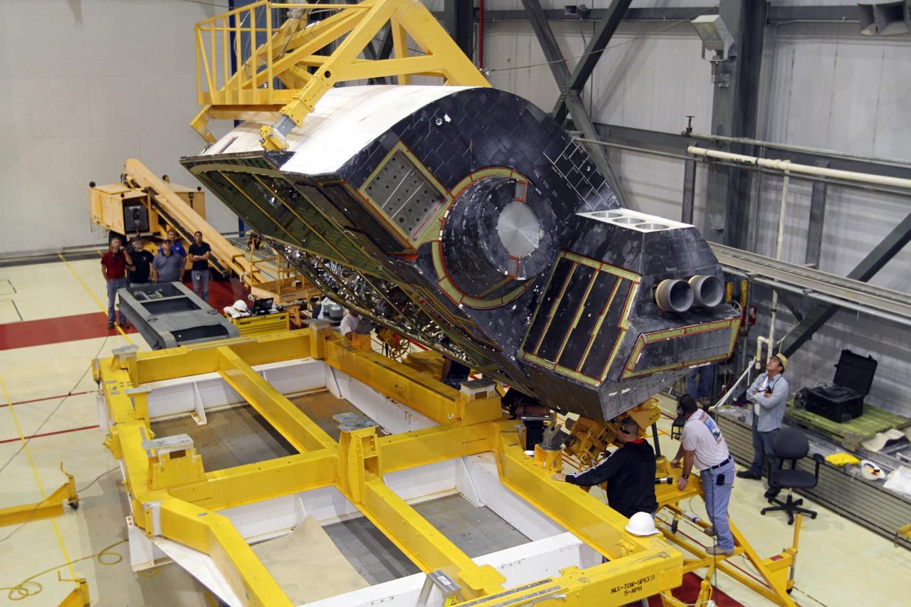 CAPE CANAVERAL, Fla. – In Orbiter Processing Facility-2 at NASA’s Kennedy Space Center in Florida, United Space Alliance technicians monitor the progress as a large crane lifts the right orbital maneuvering system OMS pod for installation on space shuttle Endeavour. The OMS pod underwent complete deservicing and cleaning at White Sands Space Harbor in New Mexico, part of the transition and retirement processing of each shuttle. Endeavour is being prepared for public display at the California Science Center in Los Angeles. Over the course of its 19-year career, Endeavour spent 299 days in space during 25 missions. For more information, visit http://www.nasa.gov/shuttle. Photo credit: NASA/Kim Shiflett