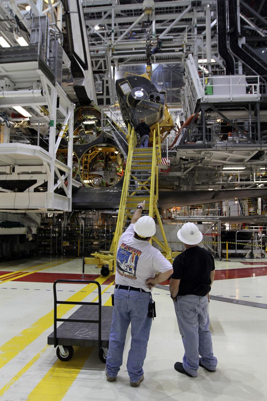 CAPE CANAVERAL, Fla. – In Orbiter Processing Facility-2 at NASA’s Kennedy Space Center in Florida, United Space Alliance technicians monitor the progress as a large crane lowers the right orbital maneuvering system OMS pod for installation on space shuttle Endeavour. The OMS pod underwent complete deservicing and cleaning at White Sands Space Harbor in New Mexico, part of the transition and retirement processing of each shuttle. Endeavour is being prepared for public display at the California Science Center in Los Angeles. Over the course of its 19-year career, Endeavour spent 299 days in space during 25 missions. For more information, visit http://www.nasa.gov/shuttle. Photo credit: NASA/Kim Shiflett