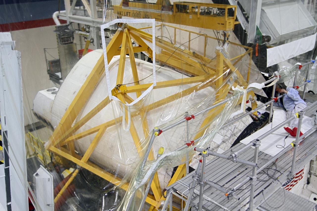 CAPE CANAVERAL, Fla. – In Orbiter Processing Facility-2 at NASA’s Kennedy Space Center in Florida, United Space Alliance technicians assist with removal of the large crane that was used to lower the right orbital maneuvering system OMS pod onto space shuttle Endeavour. The OMS pod underwent complete deservicing and cleaning at White Sands Space Harbor in New Mexico, part of the transition and retirement processing of each shuttle. Endeavour is being prepared for public display at the California Science Center in Los Angeles. Over the course of its 19-year career, Endeavour spent 299 days in space during 25 missions. For more information, visit http://www.nasa.gov/shuttle. Photo credit: NASA/Kim Shiflett