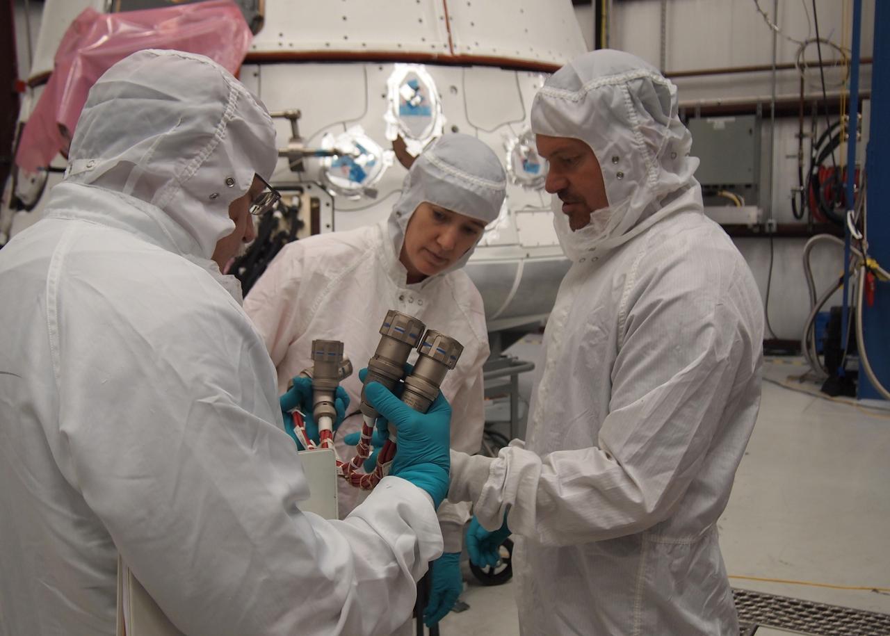 CAPE CANAVERAL, Fla. -- NASA astronaut Megan McArthur, center, takes part in a crew equipment interface test CEIT in order to become familiar with the Space Exploration Technologies Corp. SpaceX Dragon capsule prior to its scheduled April 30 liftoff. The interface test inside a processing hangar at Cape Canaveral Air Force Station's Space Launch Complex-40 was part of prelaunch preparations for the company's next demonstration test flight for NASA's Commercial Orbital Transportation Services COTS program. Under COTS, NASA has partnered with two private companies to launch cargo safely to the International Space Station. United Space Alliance technicians, Dan Nelson, left, and Chris Hardcastle, right, show McArthur two power connectors that are similar to the ones astronauts will use to provide power to Dragon once at the station.    CEIT is an activity that dates back to NASA's Space Shuttle Program, providing astronauts on Earth an opportunity to work with the actual hardware they would use in space. This exercise gave astronauts and engineers the opportunity to assess the compatibility of the equipment and systems aboard Dragon with the procedures to be used by the flight crew and flight controllers once the capsule is berthed at the space station. For more information, visit www.nasa.gov/exploration/commercial/cargo/spacex_index.html. Image courtesy: SpaceX/Paul Bonness