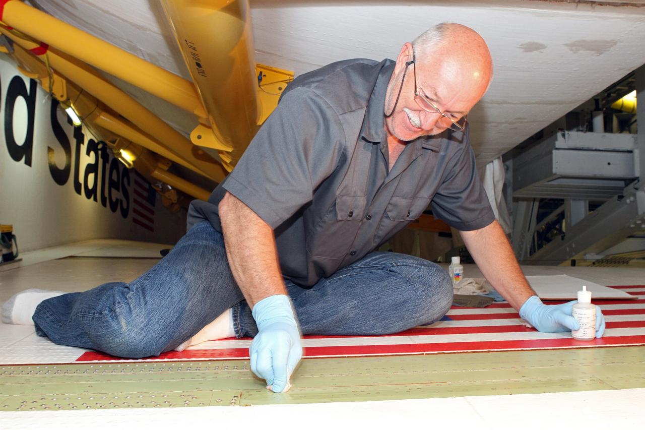 CAPE CANAVERAL, Fla. – Inside Orbiter Processing Facility-2 at NASA's Kennedy Space Center in Florida, Mike Williams, a thermal protection system technician with United Space Alliance, crouches on space shuttle Endeavour's right wing as he prepares the wing surface for tile bonding.    Ongoing transition and retirement activities are preparing the spacecraft for public display at the California Science Center in Los Angeles. Endeavour flew 25 missions during its 19-year career. Photo credit: NASA/Cory Huston