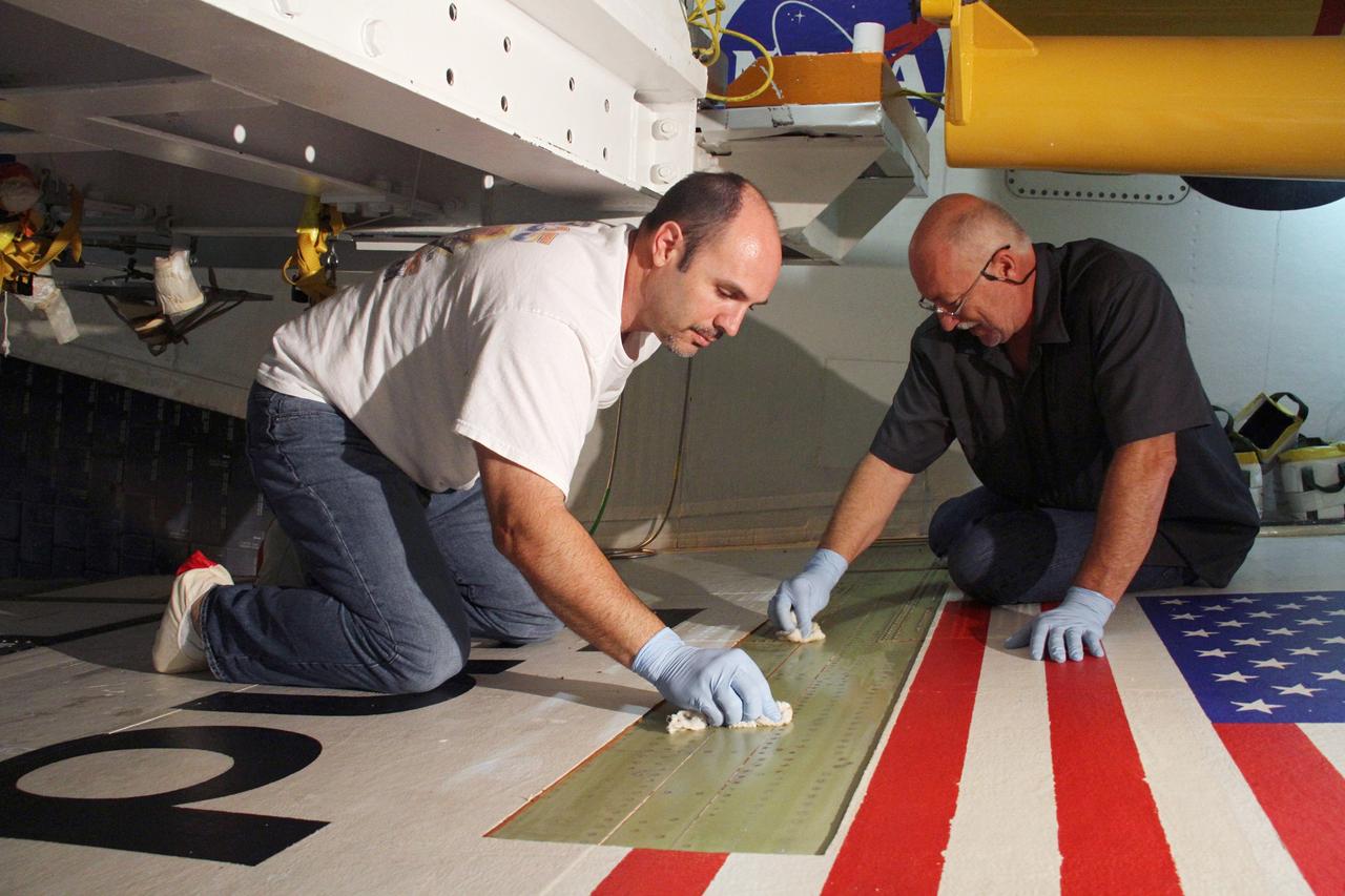 CAPE CANAVERAL, Fla. – Jeremy Schwarz, left, quality assurance technician, and Mike Williams, right, a thermal protection system technician, both with United Space Alliance, prepare the right wing of space shuttle Endeavour for tile bonding. Endeavour is inside Orbiter Processing Facility-2 at NASA's Kennedy Space Center in Florida.    Ongoing transition and retirement activities are preparing the spacecraft for public display at the California Science Center in Los Angeles. Endeavour flew 25 missions during its 19-year career. Photo credit: NASA/Cory Huston