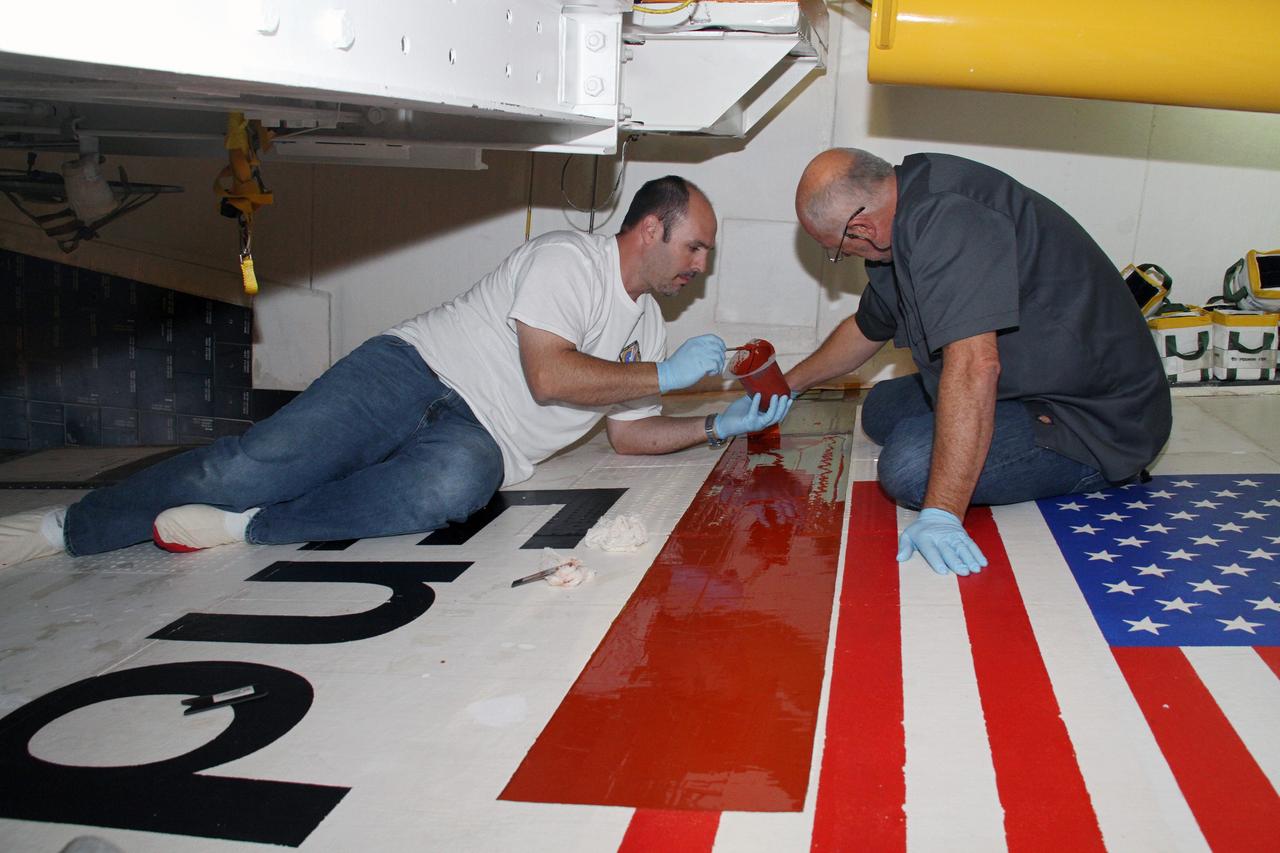 CAPE CANAVERAL, Fla. – Jeremy Schwarz, left, quality assurance technician, and Mike Williams, right, a thermal protection system technician, both with United Space Alliance, apply adhesive to space shuttle Endeavour's right wing. The work is being done in preparation for tile bonding. Endeavour is inside Orbiter Processing Facility-2 at NASA's Kennedy Space Center in Florida.    Ongoing transition and retirement activities are preparing the spacecraft for public display at the California Science Center in Los Angeles. Endeavour flew 25 missions during its 19-year career. Photo credit: NASA/Cory Huston