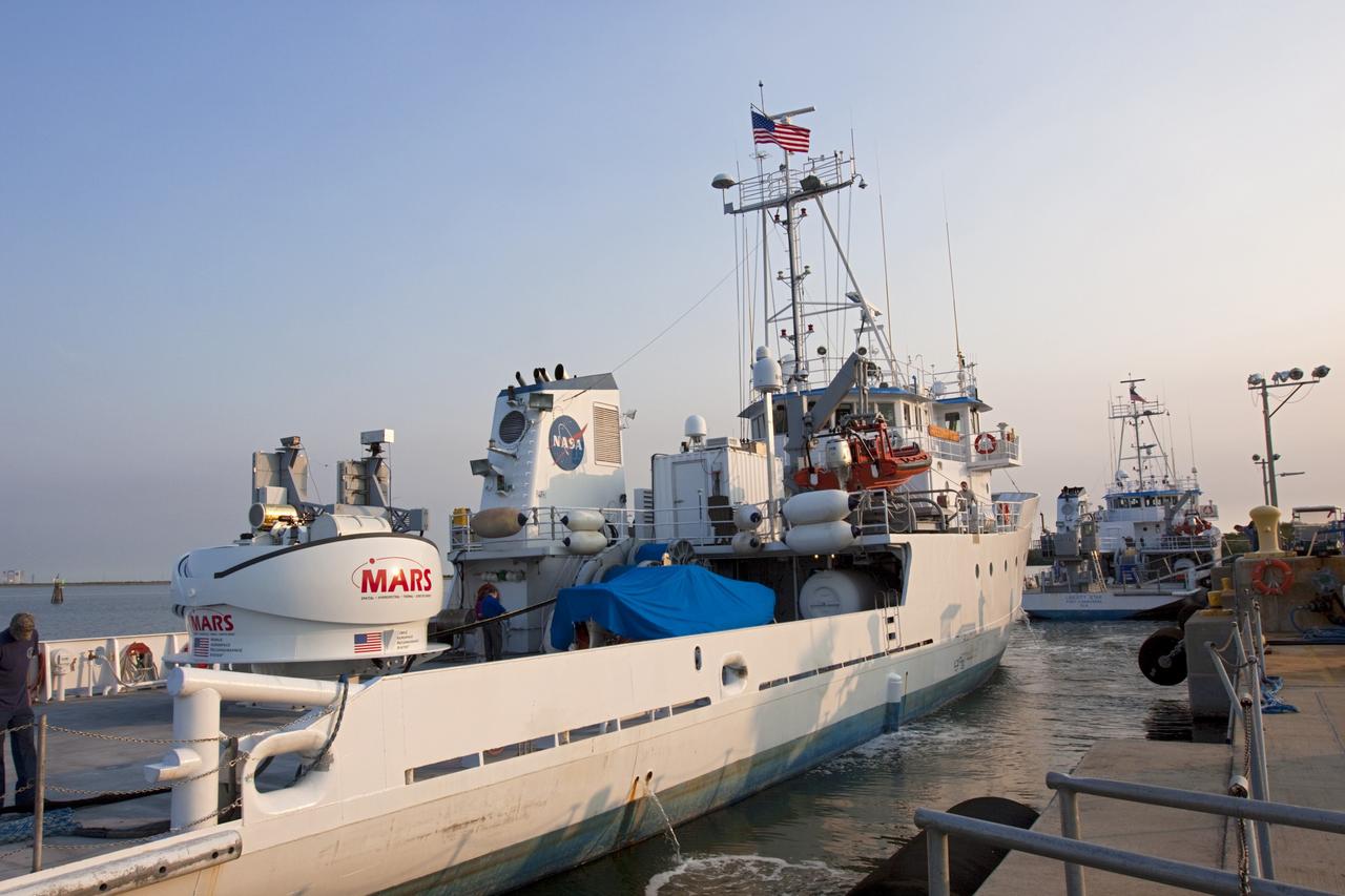 CAPE CANAVERAL, Fla. -- NASA’s Mobile Aerospace Reconnaissance System, or MARS, is secured aboard NASA’s Freedom Star boat near Hangar AE at Cape Canaveral Air Force Station in Florida. MARS is being prepared for a day of testing after departing from Port Canaveral out to the Atlantic Ocean.    MARS, run by NASA’s Langley Research Center in Hampton, Va., with its spatial, hyperspectral, thermal, and directed energy capabilities will be used for thermal imaging testing for the upcoming SpaceX Falcon 9 and Dragon capsule test flight to the International Space Station. During today’s test, the MARS X-band radar and kineto tracking mount KTM were tested to ensure that they were synchronized to receive a rocket launch feed. The radar was used to identify an object to see if the KTM could lock on to and track it. The MARS team performed maintenance on the system, confirmed communications links, and tested the design of the mounting system and environmental enclosure. Photo credit: NASA/Jim Grossmann