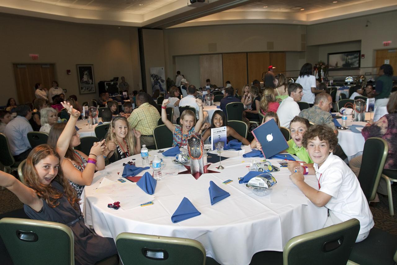 CAPE CANAVERAL, Fla. - Winners of the NASA OPTIMUS PRIME Spinoff Video Contest show their excitement in the Debus Conference Center of the Kennedy Space Center Visitor Complex. The contest challenged students in grades three through 12 to study NASA spinoff technologies and produce short, creative videos promoting their favorites. The NASA Goddard Space Flight Center's Innovative Partnerships Office in Greenbelt, Md., designed the contest to help students see the benefits of NASA technology here on Earth. NASA collaborated with Hasbro in using the OPTIMUS PRIME character. Photo credit: NASA/Jim Grossmann