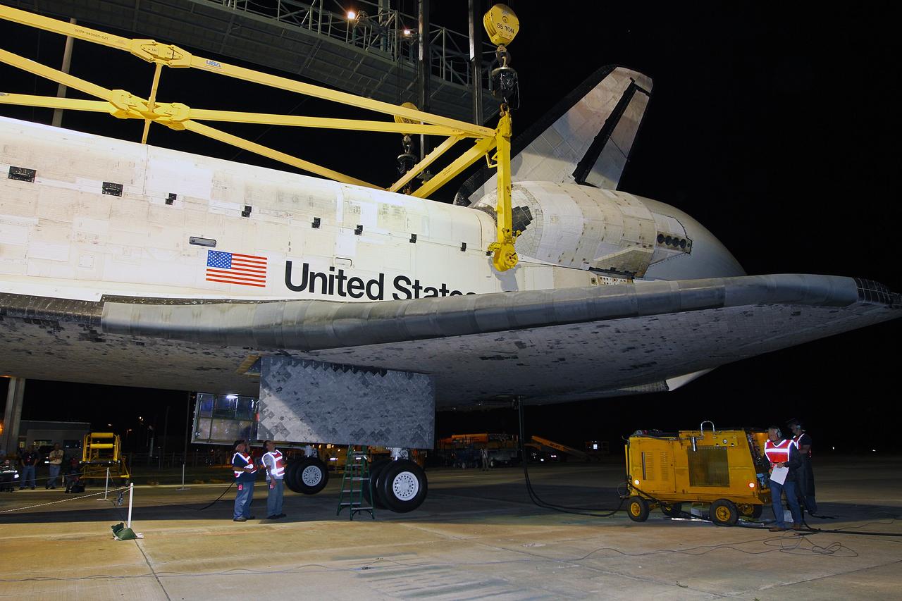 CAPE CANAVERAL, Fla. – Before daybreak at the Shuttle Landing Facility at NASA’s Kennedy Space Center in Florida, workers inspect space shuttle Discovery, suspended from the mate-demate device with the support of the yellow sling. Operations are under way to position Discovery on top of a Shuttle Carrier Aircraft in preparation for its departure from Kennedy on Tuesday. The device, known as the MDD, is a large gantry-like steel structure used to hoist a shuttle off the ground and position it onto the back of the aircraft, or SCA. The SCA is a Boeing 747 jet, originally manufactured for commercial use, which was modified by NASA to transport the shuttles between destinations on Earth. The SCA designated NASA 905 is assigned to the remaining ferry missions, delivering the shuttles to their permanent public display sites. NASA 905 is scheduled to ferry Discovery to the Washington Dulles International Airport in Virginia on April 17, after which the shuttle will be placed on display in the Smithsonian's National Air and Space Museum Steven F. Udvar-Hazy Center. For more information on the SCA, visit http://www.nasa.gov/centers/dryden/news/FactSheets/FS-013-DFRC.html. For more information on shuttle transition and retirement activities, visit http://www.nasa.gov/transition. Photo credit: NASA/Kim Shiflett