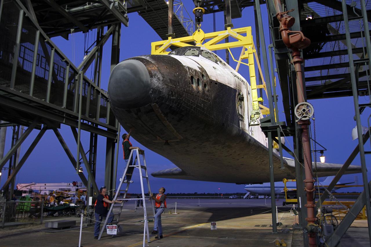 CAPE CANAVERAL, Fla. – As the sun rises over the Shuttle Landing Facility at NASA’s Kennedy Space Center in Florida, workers at the mate-demate device inspect space shuttle Discovery to ensure that it is ready for placement on top of a Shuttle Carrier Aircraft.     The device, known as the MDD, is a large gantry-like steel structure used to hoist a shuttle off the ground and position it onto the back of the aircraft, or SCA. The SCA is a Boeing 747 jet, originally manufactured for commercial use, which was modified by NASA to transport the shuttles between destinations on Earth. The SCA designated NASA 905 is assigned to the remaining ferry missions, delivering the shuttles to their permanent public display sites.  NASA 905 is scheduled to ferry Discovery to the Washington Dulles International Airport in Virginia on April 17, after which the shuttle will be placed on display in the Smithsonian's National Air and Space Museum Steven F. Udvar-Hazy Center. For more information on the SCA, visit http://www.nasa.gov/centers/dryden/news/FactSheets/FS-013-DFRC.html. For more information on shuttle transition and retirement activities, visit http://www.nasa.gov/transition. Photo credit: NASA/Kim Shiflett