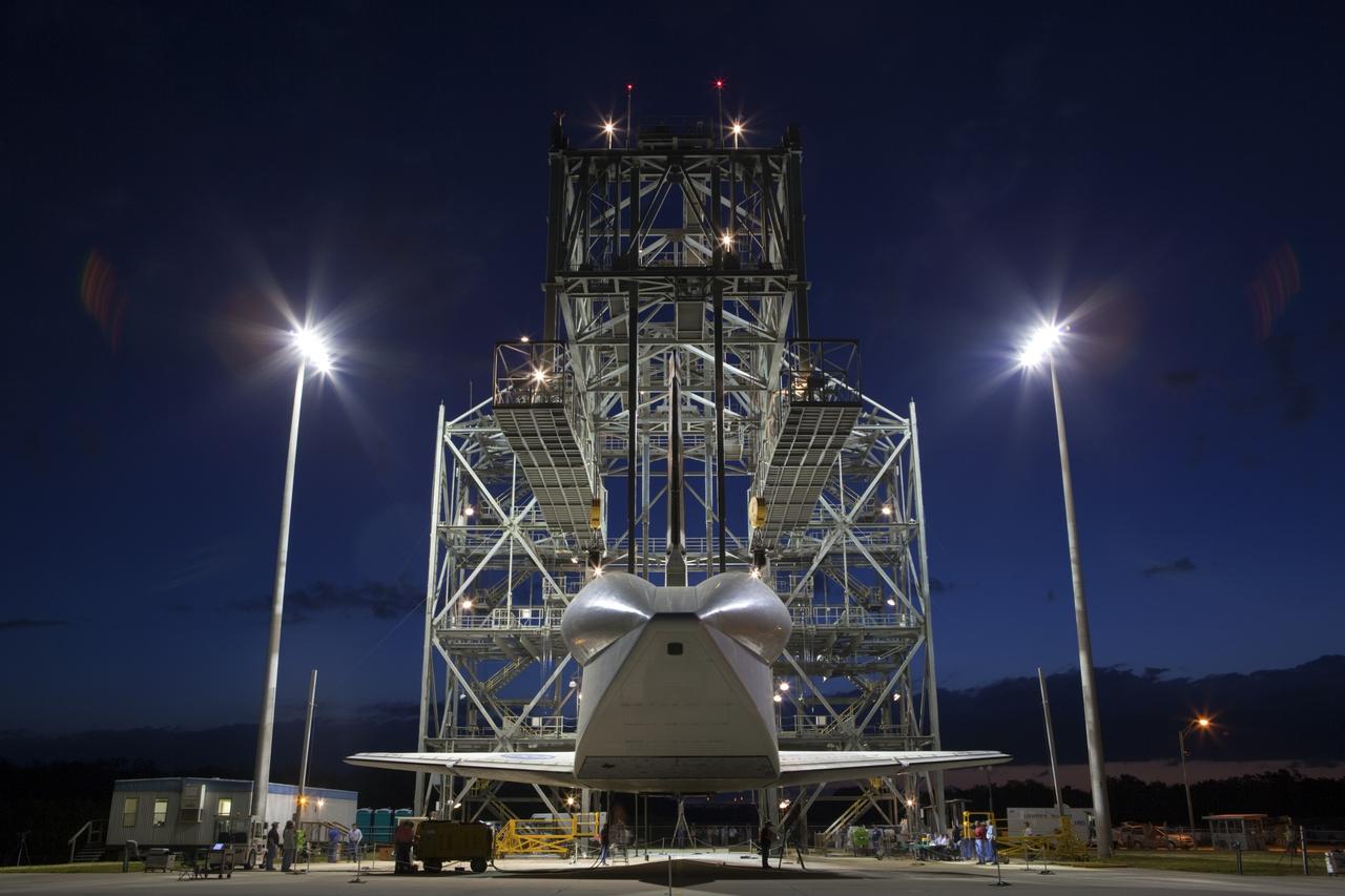 CAPE CANAVERAL, Fla. – Before daybreak at the Shuttle Landing Facility at NASA’s Kennedy Space Center in Florida, space shuttle Discovery hovers above the ground at the mate-demate device. Operations are under way to position Discovery on top of a Shuttle Carrier Aircraft in preparation for its departure from Kennedy on Tuesday. A tail cone has been installed over Discovery’s three replica shuttle main engines to reduce aerodynamic drag and turbulence during the ferry flight.    The device, known as the MDD, is a large gantry-like steel structure used to hoist a shuttle off the ground and position it onto the back of the aircraft, or SCA. The SCA is a Boeing 747 jet, originally manufactured for commercial use, which was modified by NASA to transport the shuttles between destinations on Earth. The SCA designated NASA 905 is assigned to the remaining ferry missions, delivering the shuttles to their permanent public display sites.  NASA 905 is scheduled to ferry Discovery to the Washington Dulles International Airport in Virginia on April 17, after which the shuttle will be placed on display in the Smithsonian's National Air and Space Museum Steven F. Udvar-Hazy Center. For more information on the SCA, visit http://www.nasa.gov/centers/dryden/news/FactSheets/FS-013-DFRC.html. For more information on shuttle transition and retirement activities, visit http://www.nasa.gov/transition. Photo credit: NASA/Dimitri Gerondidakis