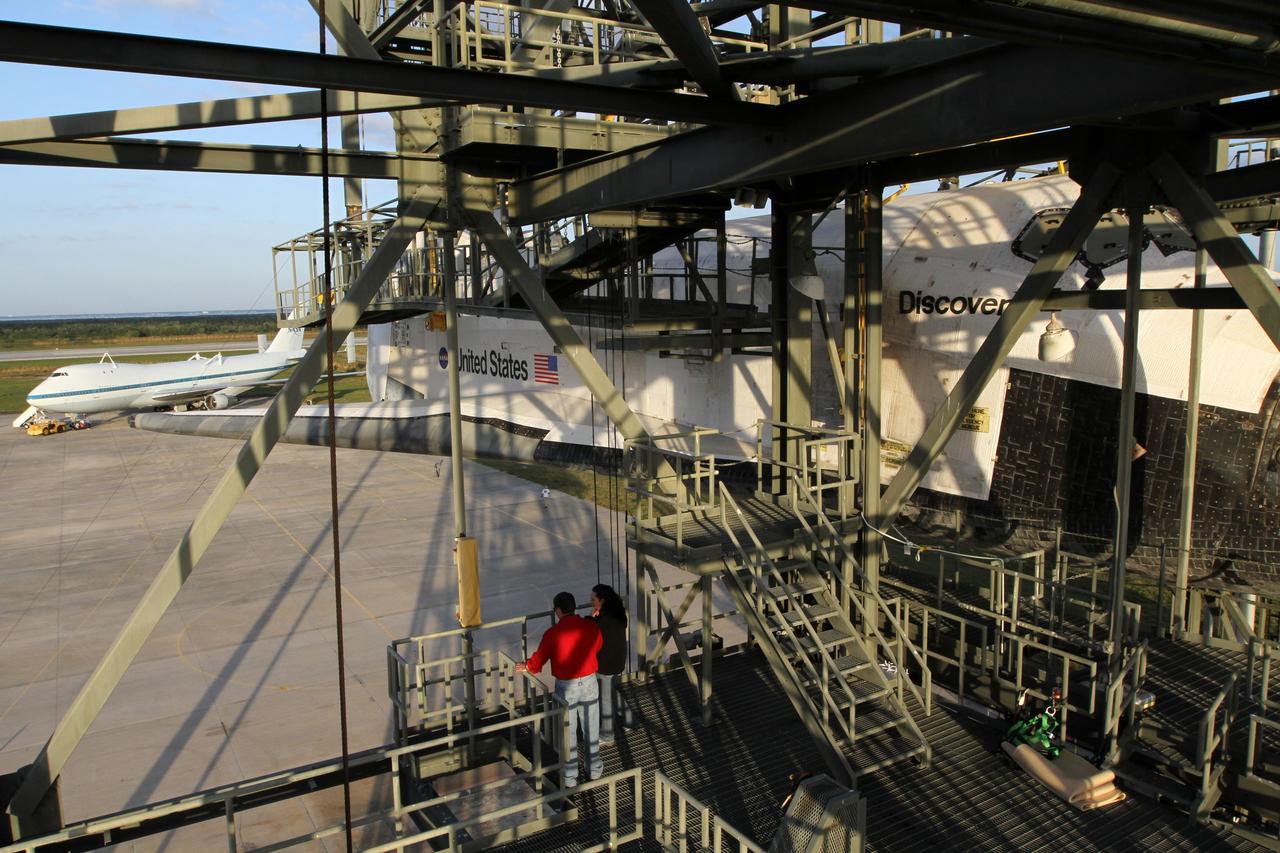 CAPE CANAVERAL, Fla. – At the Shuttle Landing Facility at NASA’s Kennedy Space Center in Florida, space shuttle Discovery is suspended 60 feet off the ground inside the mate-demate device in preparation for the arrival of the Shuttle Carrier Aircraft, in the background.    The device, known as the MDD, is a large gantry-like steel structure used to hoist a shuttle off the ground and position it onto the back of the aircraft, or SCA. This SCA, designated NASA 905, is a Boeing 747 jet originally manufactured for commercial use, which was modified by NASA to transport the shuttles between destinations on Earth. NASA 905 is assigned to the remaining ferry missions, delivering the shuttles to their permanent public display sites. Discovery’s new home will be the Smithsonian's National Air and Space Museum Steven F. Udvar-Hazy Center in Chantilly, Va. For more information on the SCA, visit http://www.nasa.gov/centers/dryden/news/FactSheets/FS-013-DFRC.html. For more information on shuttle transition and retirement activities, visit http://www.nasa.gov/transition. Photo credit: NASA/Kim Shiflett