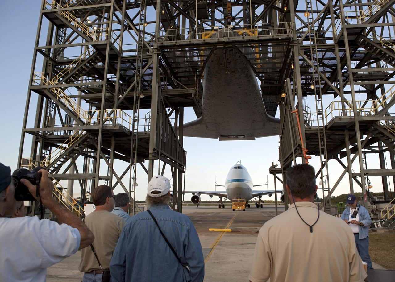 CAPE CANAVERAL, Fla. – At the Shuttle Landing Facility at NASA’s Kennedy Space Center in Florida, workers are standing by for the arrival of the Shuttle Carrier Aircraft under space shuttle Discovery suspended 60 feet off the ground inside the mate-demate device.      The device, known as the MDD, is a large gantry-like steel structure used to hoist a shuttle off the ground and position it onto the back of the aircraft, or SCA. The SCA is a Boeing 747 jet, originally manufactured for commercial use, which was modified by NASA to transport the shuttles between destinations on Earth. This SCA, designated NASA 905, is assigned to the remaining ferry missions, delivering the shuttles to their permanent public display sites.  NASA 905 is scheduled to ferry Discovery to the Washington Dulles International Airport in Virginia on April 17, after which the shuttle will be placed on display in the Smithsonian's National Air and Space Museum Steven F. Udvar-Hazy Center. For more information on the SCA, visit http://www.nasa.gov/centers/dryden/news/FactSheets/FS-013-DFRC.html. For more information on shuttle transition and retirement activities, visit http://www.nasa.gov/transition. Photo credit: NASA/Dimitri Gerondidakis