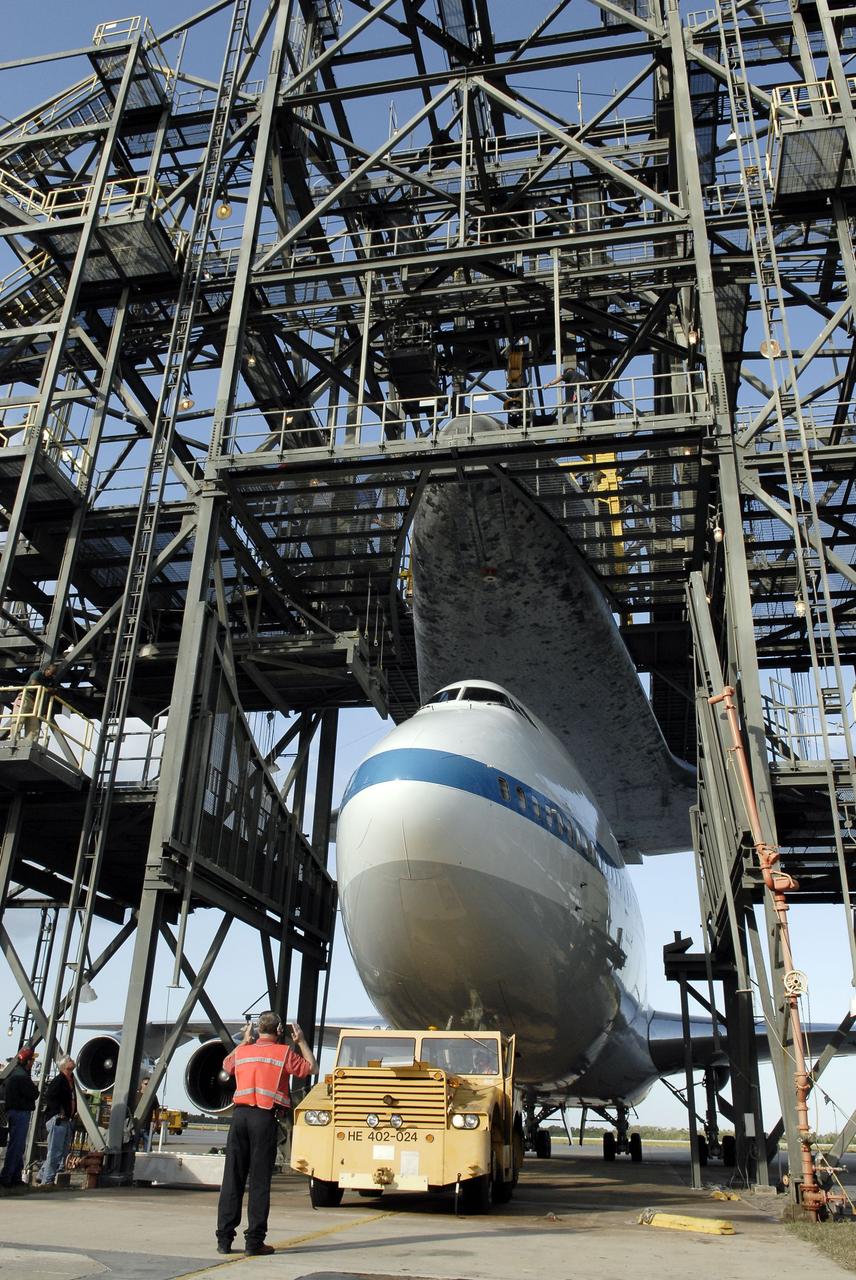 CAPE CANAVERAL, Fla. – At the Shuttle Landing Facility at NASA’s Kennedy Space Center in Florida, a worker guides the Shuttle Carrier Aircraft into position under space shuttle Discovery suspended in the mate-demate device.    The device, known as the MDD, is a large gantry-like steel structure used to hoist a shuttle off the ground and position it onto the back of the aircraft, or SCA. The SCA is a Boeing 747 jet, originally manufactured for commercial use, which was modified by NASA to transport the shuttles between destinations on Earth. This SCA, designated NASA 905, is assigned to the remaining ferry missions, delivering the shuttles to their permanent public display sites.  NASA 905 is scheduled to ferry Discovery to the Washington Dulles International Airport in Virginia on April 17, after which the shuttle will be placed on display in the Smithsonian's National Air and Space Museum Steven F. Udvar-Hazy Center. For more information on the SCA, visit http://www.nasa.gov/centers/dryden/news/FactSheets/FS-013-DFRC.html. For more information on shuttle transition and retirement activities, visit http://www.nasa.gov/transition. Photo credit: NASA/Tim Jacobs