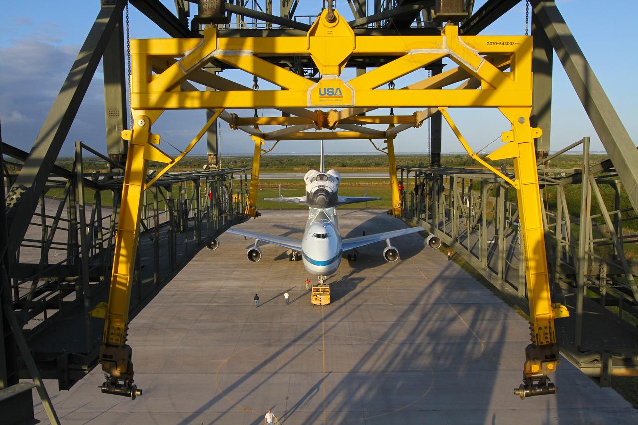CAPE CANAVERAL, Fla. – The Shuttle Carrier Aircraft carrying space shuttle Discovery backs out of the Shuttle Landing Facility's mate-demate device at NASA’s Kennedy Space Center in Florida. The device, known as the MDD, is a large gantry-like steel structure used to hoist a shuttle off the ground and position it onto the back of the aircraft, or SCA. The SCA is a Boeing 747 jet that was originally manufactured for commercial use and modified by NASA to transport the shuttles between destinations on Earth. This SCA, designated NASA 905, is assigned to the remaining ferry missions, delivering the shuttles to their permanent public display sites. NASA 905 is scheduled to ferry Discovery to the Washington Dulles International Airport in Virginia on April 17, after which the shuttle will be placed on display in the Smithsonian's National Air and Space Museum Steven F. Udvar-Hazy Center. For more information on the SCA, visit http://www.nasa.gov/centers/dryden/news/FactSheets/FS-013-DFRC.html. For more information on shuttle transition and retirement activities, visit http://www.nasa.gov/transition. Photo credit: NASA/Kim Shiflett