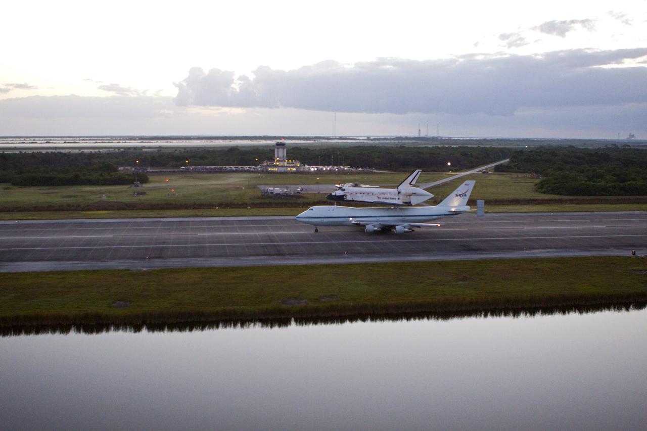 CAPE CANAVERAL, Fla. – In the early morning hours at NASA Kennedy Space Center’s Shuttle Landing Facility in Florida, the Shuttle Carrier Aircraft, or SCA, with space shuttle Discovery secured atop, taxies down the runway for a takeoff at 7 a.m. EDT. In the background is the midfield air traffic control tower. The aircraft, known as an SCA, is a Boeing 747 jet, originally manufactured for commercial use, which was modified by NASA to transport the shuttles between destinations on Earth. This SCA, designated NASA 905, is assigned to the remaining ferry missions, delivering the shuttles to their permanent public display sites. NASA 905 is scheduled to ferry Discovery to the Washington Dulles International Airport in Virginia on April 17, after which the shuttle will be placed on display in the Smithsonian’s National Air and Space Museum, Steven F. Udvar-Hazy Center in Chantilly, Va. For more information on the SCA, visit http://www.nasa.gov/centers/dryden/news/FactSheets/FS-013-DFRC.html. For more information on shuttle transition and retirement activities, visit http://www.nasa.gov/transition. Photo credit: NASA/Glenn Benson
