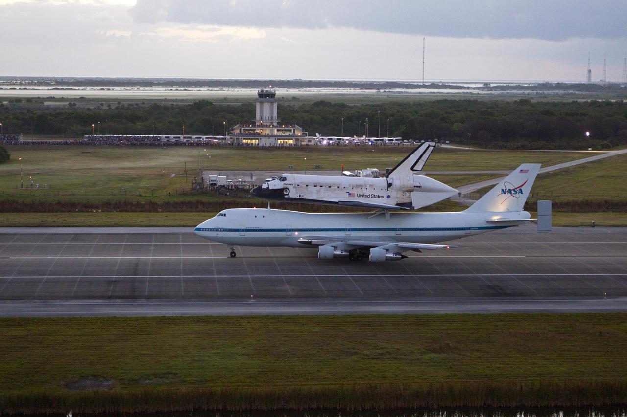 CAPE CANAVERAL, Fla. – In the early morning hours at NASA Kennedy Space Center’s Shuttle Landing Facility in Florida, the Shuttle Carrier Aircraft, or SCA, with space shuttle Discovery secured atop, taxies down the runway for a takeoff at 7 a.m. EDT. In the background is the midfield air traffic control tower. The aircraft, known as an SCA, is a Boeing 747 jet, originally manufactured for commercial use, which was modified by NASA to transport the shuttles between destinations on Earth. This SCA, designated NASA 905, is assigned to the remaining ferry missions, delivering the shuttles to their permanent public display sites. NASA 905 is scheduled to ferry Discovery to the Washington Dulles International Airport in Virginia on April 17, after which the shuttle will be placed on display in the Smithsonian’s National Air and Space Museum, Steven F. Udvar-Hazy Center in Chantilly, Va. For more information on the SCA, visit http://www.nasa.gov/centers/dryden/news/FactSheets/FS-013-DFRC.html. For more information on shuttle transition and retirement activities, visit http://www.nasa.gov/transition. Photo credit: NASA/Glenn Benson