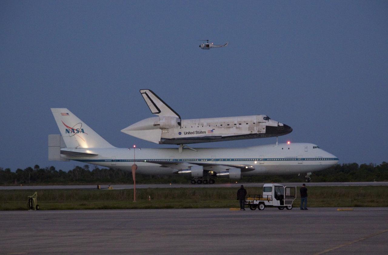 CAPE CANAVERAL, Fla. – Space shuttle Discovery, mounted to a Shuttle Carrier Aircraft, slowly rolls along the runway of the Shuttle Landing Facility at NASA's Kennedy Space Center in Florida. The duo is set to begin their 3 1/2 hour ferry flight to the Washington Dulles International Airport in Virginia at about 7 a.m. EDT. Above the two craft is a NASA helicopter covering the departure. Discovery is leaving Kennedy after more than 28 years of service beginning with its arrival on the space coast Nov. 9, 1983. Discovery first launched to space Aug. 30, 1984, on the STS-41D mission. Discovery is the agency's most-flown shuttle with 39 missions, more than 148 million miles and a total of one year in space. Discovery is set to move to the Smithsonian's National Air and Space Museum Steven F. Udvar-Hazy Center on April 19 where it will be placed on public display. For more information on the SCA, visit http://www.nasa.gov/centers/dryden/news/FactSheets/FS-013-DFRC.html. For more information on shuttle transition and retirement activities, visit http://www.nasa.gov/transition. Photo credit: NASA/Jim Grossmann