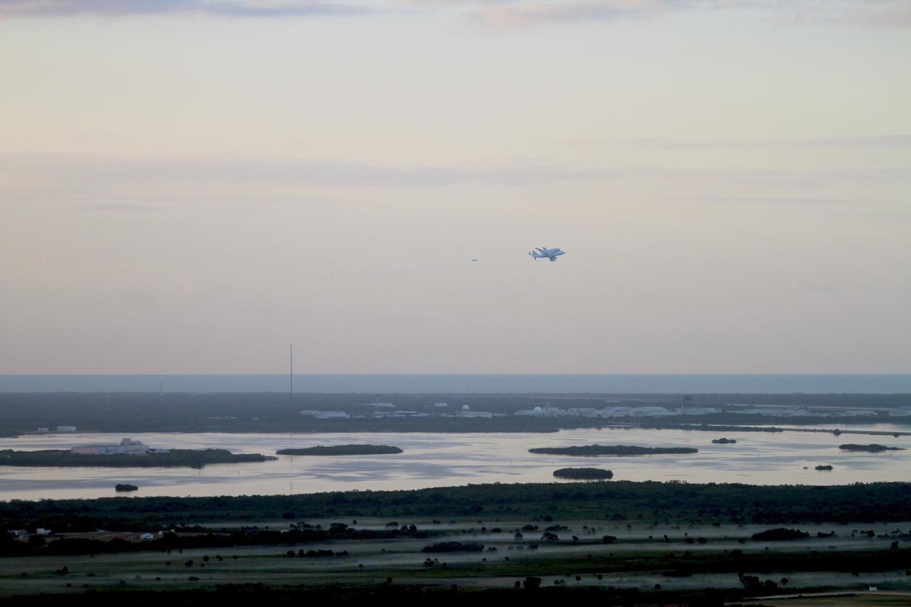 CAPE CANAVERAL, Fla. – The Shuttle Carrier Aircraft transporting space shuttle Discovery flies over the hangars in the Industrial Area on Cape Canaveral Air Force Station after taking off from Kennedy Space Center’s Shuttle Landing Facility at 7 a.m. EDT. The duo are heading south to fly over Brevard County’s beach communities, offering residents the opportunity to see the shuttle before it leaves the Space Coast for the last time.     The aircraft, known as an SCA, is a Boeing 747 jet, originally manufactured for commercial use, which was modified by NASA to transport the shuttles between destinations on Earth. This SCA, designated NASA 905, is assigned to the remaining ferry missions, delivering the shuttles to their permanent public display sites.  NASA 905 is scheduled to ferry Discovery to the Washington Dulles International Airport in Virginia on April 17, after which the shuttle will be placed on display in the Smithsonian's National Air and Space Museum Steven F. Udvar-Hazy Center. For more information on the SCA, visit http://www.nasa.gov/centers/dryden/news/FactSheets/FS-013-DFRC.html. For more information on shuttle transition and retirement activities, visit http://www.nasa.gov/transition. Photo credit: NASA/Lorne Mathre