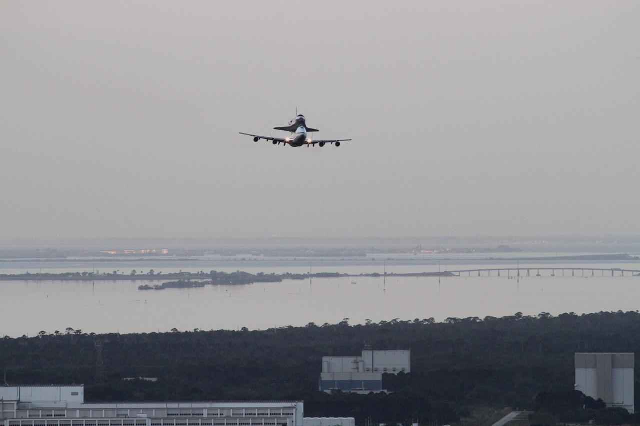 CAPE CANAVERAL, Fla. – The Shuttle Carrier Aircraft transporting space shuttle Discovery flies over NASA Kennedy Space Center’s Operations and Checkout Building, left, Hypergolic Maintenance Facility, center, and Canister Rotation Facility, right, following a flyby of Brevard County’s beach communities, offering residents the opportunity to see the shuttle before it leaves the Space Coast for the last time. The duo took off from Kennedy’s Shuttle Landing Facility at 7 a.m. EDT. The aircraft, known as an SCA, is a Boeing 747 jet, originally manufactured for commercial use, which was modified by NASA to transport the shuttles between destinations on Earth. This SCA, designated NASA 905, is assigned to the remaining ferry missions, delivering the shuttles to their permanent public display sites. NASA 905 is scheduled to ferry Discovery to the Washington Dulles International Airport in Virginia on April 17, after which the shuttle will be placed on display in the Smithsonian's National Air and Space Museum Steven F. Udvar-Hazy Center. For more information on the SCA, visit http://www.nasa.gov/centers/dryden/news/FactSheets/FS-013-DFRC.html. For more information on shuttle transition and retirement activities, visit http://www.nasa.gov/transition. Photo credit: NASA/Lorne Mathre