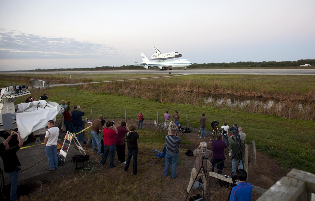 CAPE CANAVERAL, Fla. – Media snap photos as space shuttle Discovery, mounted to a Shuttle Carrier Aircraft, slowly rolls along the runway of the Shuttle Landing Facility at NASA's Kennedy Space Center in Florida. The duo is set to begin their 3 1/2 hour ferry flight to the Washington Dulles International Airport in Virginia at about 7 a.m. EDT. Above the two craft is a NASA helicopter covering the departure. Discovery is leaving Kennedy after more than 28 years of service beginning with its arrival on the space coast Nov. 9, 1983. Discovery first launched to space Aug. 30, 1984, on the STS-41D mission. Discovery is the agency's most-flown shuttle with 39 missions, more than 148 million miles and a total of one year in space. Discovery is set to move to the Smithsonian's National Air and Space Museum Steven F. Udvar-Hazy Center on April 19 where it will be placed on public display. For more information on the SCA, visit http://www.nasa.gov/centers/dryden/news/FactSheets/FS-013-DFRC.html. For more information on shuttle transition and retirement activities, visit http://www.nasa.gov/transition. Photo credit: NASA/Frankie Martin