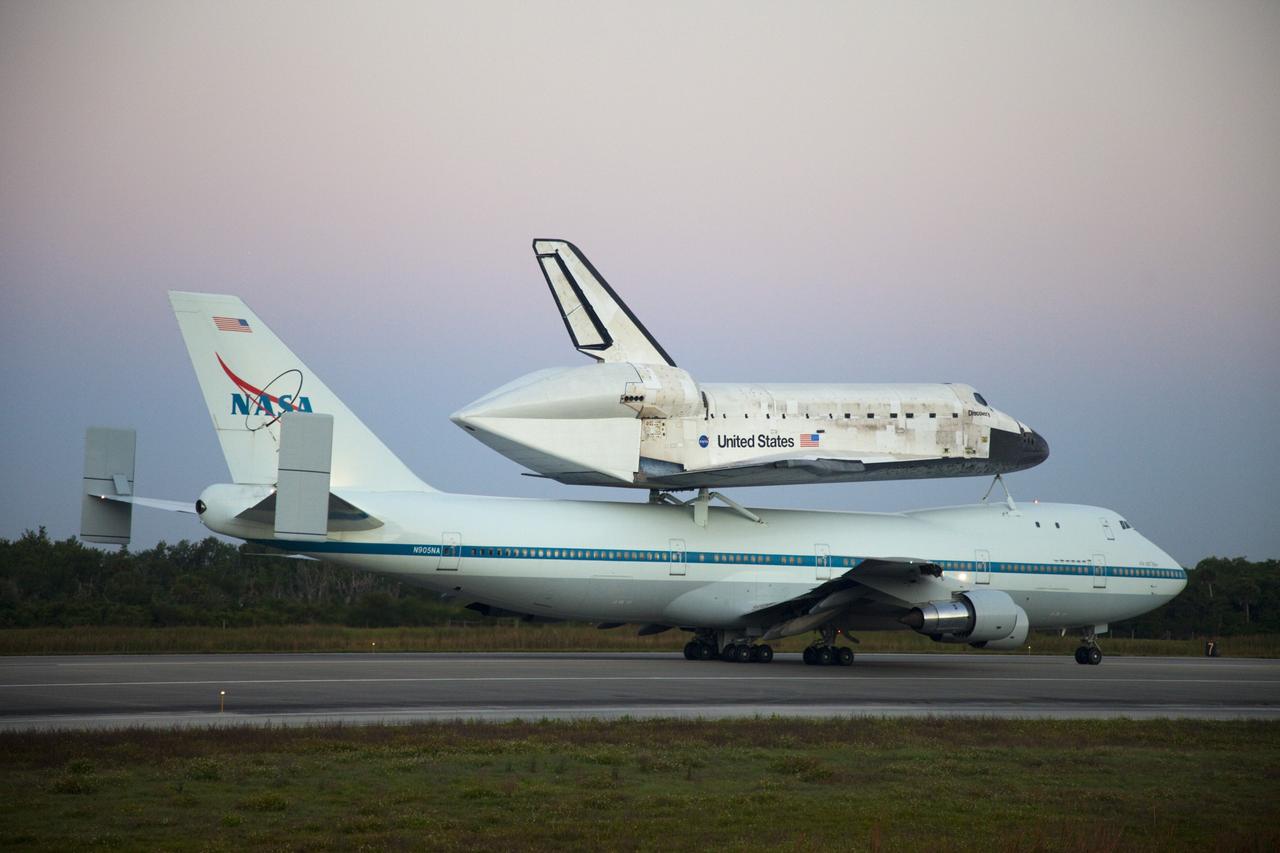 CAPE CANAVERAL, Fla. – Space shuttle Discovery, mounted to a Shuttle Carrier Aircraft, slowly rolls along the runway of the Shuttle Landing Facility at NASA's Kennedy Space Center in Florida. The duo is set to begin their 3 1/2 hour ferry flight to the Washington Dulles International Airport in Virginia at about 7 a.m. EDT. Above the two craft is a NASA helicopter covering the departure. Discovery is leaving Kennedy after more than 28 years of service beginning with its arrival on the space coast Nov. 9, 1983. Discovery first launched to space Aug. 30, 1984, on the STS-41D mission. Discovery is the agency's most-flown shuttle with 39 missions, more than 148 million miles and a total of one year in space. Discovery is set to move to the Smithsonian's National Air and Space Museum Steven F. Udvar-Hazy Center on April 19 where it will be placed on public display. For more information on the SCA, visit http://www.nasa.gov/centers/dryden/news/FactSheets/FS-013-DFRC.html. For more information on shuttle transition and retirement activities, visit http://www.nasa.gov/transition. Photo credit: NASA/Frankie Martin