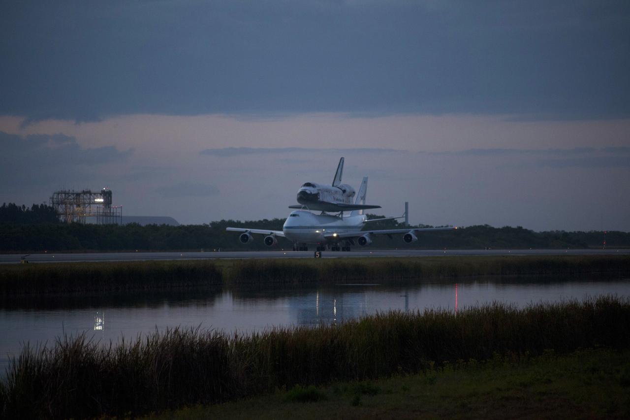 CAPE CANAVERAL, Fla. – The Shuttle Carrier Aircraft transporting space shuttle Discovery to its new home taxis down the runway past the mate/demate device as day breaks over the Shuttle Landing Facility at NASA’s Kennedy Space Center in Florida. The duo will fly south over Brevard County’s beach communities for residents to get a look at the shuttle before it leaves the Space Coast for the last time. The aircraft, known as an SCA, is a Boeing 747 jet, originally manufactured for commercial use, which was modified by NASA to transport the shuttles between destinations on Earth. This SCA, designated NASA 905, is assigned to the remaining ferry missions, delivering the shuttles to their permanent public display sites. NASA 905 is scheduled to ferry Discovery to the Washington Dulles International Airport in Virginia on April 17, after which the shuttle will be placed on display in the Smithsonian's National Air and Space Museum Steven F. Udvar-Hazy Center. For more information on the SCA, visit http://www.nasa.gov/centers/dryden/news/FactSheets/FS-013-DFRC.html. For more information on shuttle transition and retirement activities, visit http://www.nasa.gov/transition. Photo credit: NASA/Tim Powers and Rick Wetherington