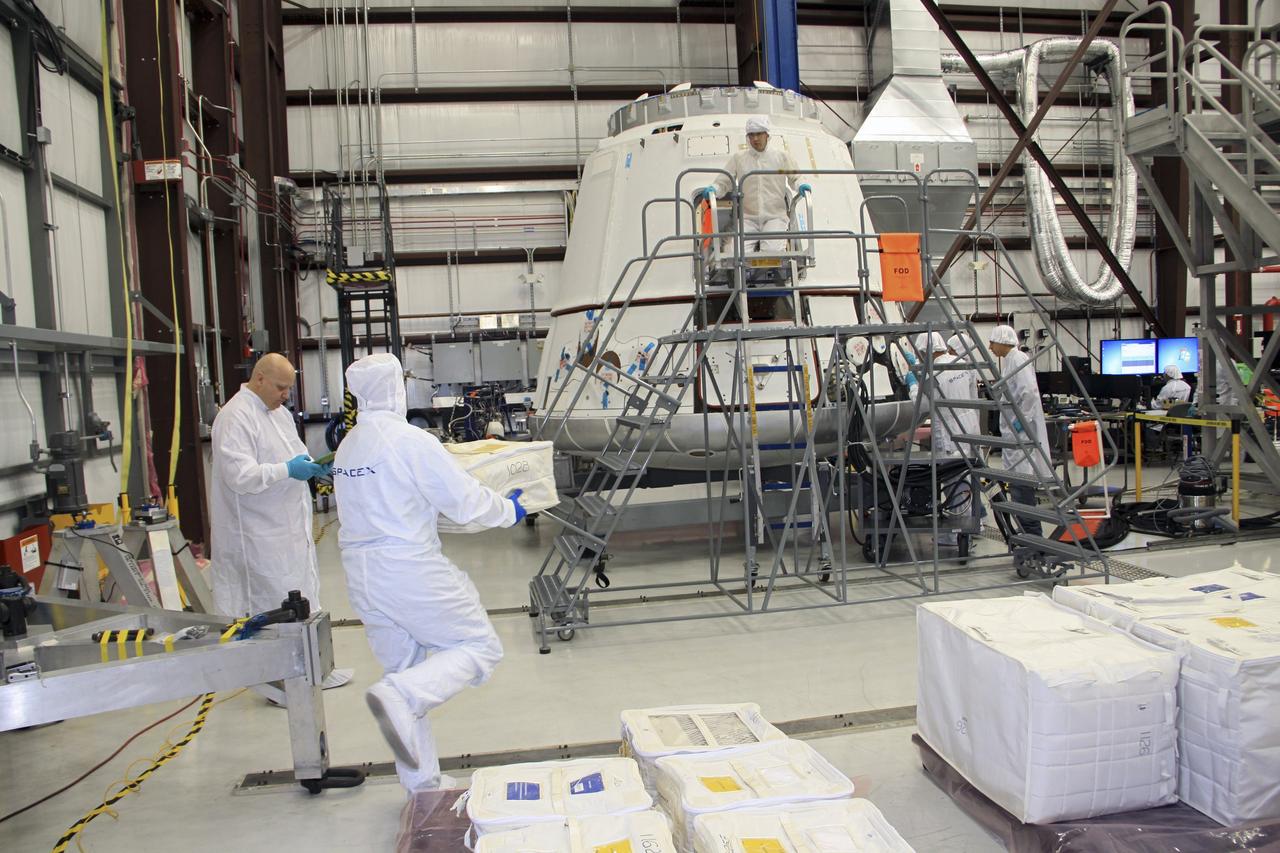 CAPE CANAVERAL, Fla. – In a processing hangar at Space Launch Complex-40 on Cape Canaveral Air Force Station in Florida, Space Exploration Technologies technicians load cargo into the Dragon capsule in preparation for its scheduled April 30 liftoff aboard a Falcon 9 rocket.    Known as SpaceX, the launch will be the company's second demonstration test flight for NASA's Commercial Orbital Transportation Services program, or COTS. During the flight, the capsule will conduct a series of checkout procedures to test and prove its systems, including rendezvous and berthing with the International Space Station. The cargo includes food and provisions for the station’s Expedition crews, such as clothing, batteries, and computer equipment. Under COTS, NASA has partnered with two private companies to launch cargo safely to the station. For more information, visit http://www.nasa.gov/spacex.  Photo credit: NASA/Jim Grossmann