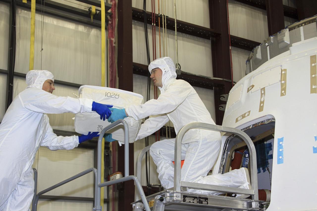 CAPE CANAVERAL, Fla. – In a processing hangar at Space Launch Complex-40 on Cape Canaveral Air Force Station in Florida, Space Exploration Technologies technicians load cargo into the Dragon capsule in preparation for its scheduled April 30 liftoff aboard a Falcon 9 rocket. Known as SpaceX, the launch will be the company's second demonstration test flight for NASA's Commercial Orbital Transportation Services program, or COTS. During the flight, the capsule will conduct a series of checkout procedures to test and prove its systems, including rendezvous and berthing with the International Space Station. The cargo includes food and provisions for the station’s Expedition crews, such as clothing, batteries, and computer equipment. Under COTS, NASA has partnered with two private companies to launch cargo safely to the station. For more information, visit http://www.nasa.gov/spacex. Photo credit: NASA/Jim Grossmann