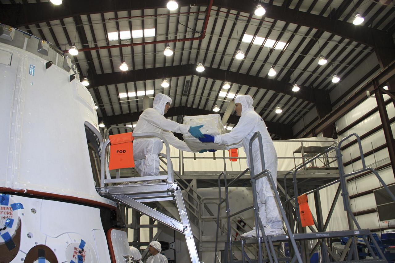 CAPE CANAVERAL, Fla. – In a processing hangar at Space Launch Complex-40 on Cape Canaveral Air Force Station in Florida, Space Exploration Technologies technicians load cargo into the Dragon capsule in preparation for its scheduled April 30 liftoff aboard a Falcon 9 rocket.    Known as SpaceX, the launch will be the company's second demonstration test flight for NASA's Commercial Orbital Transportation Services program, or COTS. During the flight, the capsule will conduct a series of checkout procedures to test and prove its systems, including rendezvous and berthing with the International Space Station. The cargo includes food and provisions for the station’s Expedition crews, such as clothing, batteries, and computer equipment. Under COTS, NASA has partnered with two private companies to launch cargo safely to the station. For more information, visit http://www.nasa.gov/spacex.  Photo credit: NASA/Jim Grossmann