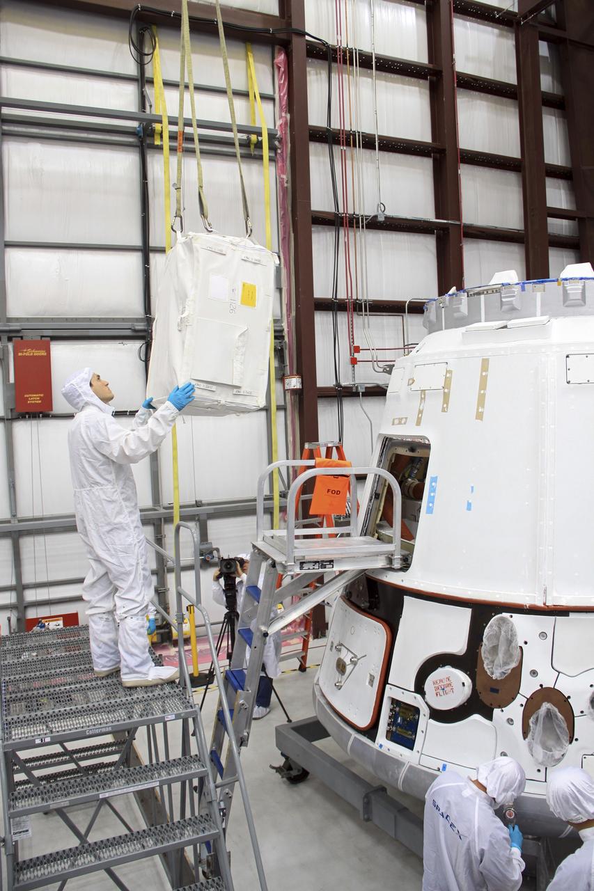 CAPE CANAVERAL, Fla. – In a processing hangar at Space Launch Complex-40 on Cape Canaveral Air Force Station in Florida, a cargo bag is lowered into the hands of a Space Exploration Technologies technician who will load it into the Dragon capsule in preparation for its scheduled April 30 liftoff aboard a Falcon 9 rocket.    Known as SpaceX, the launch will be the company's second demonstration test flight for NASA's Commercial Orbital Transportation Services program, or COTS. During the flight, the capsule will conduct a series of checkout procedures to test and prove its systems, including rendezvous and berthing with the International Space Station. The cargo includes food and provisions for the station’s Expedition crews, such as clothing, batteries, and computer equipment. Under COTS, NASA has partnered with two private companies to launch cargo safely to the station. For more information, visit http://www.nasa.gov/spacex.  Photo credit: NASA/Jim Grossmann