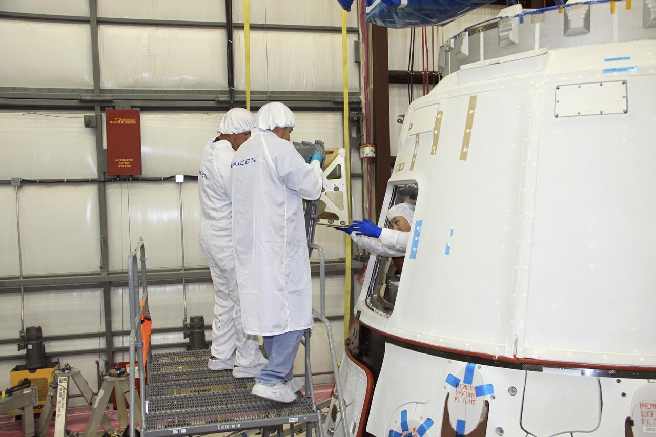 CAPE CANAVERAL, Fla. – In a processing hangar at Space Launch Complex-40 on Cape Canaveral Air Force Station in Florida, Space Exploration Technologies technicians prepare to close the hatch of the Dragon capsule.  The hatch was open for cargo to be stowed in the capsule in preparation for its scheduled April 30 liftoff aboard a Falcon 9 rocket.      Known as SpaceX, the launch will be the company's second demonstration test flight for NASA's Commercial Orbital Transportation Services program, or COTS. During the flight, the capsule will conduct a series of checkout procedures to test and prove its systems, including rendezvous and berthing with the International Space Station. The cargo includes food and provisions for the station’s Expedition crews, such as clothing, batteries, and computer equipment. Under COTS, NASA has partnered with two private companies to launch cargo safely to the station. For more information, visit http://www.nasa.gov/spacex.  Photo credit: NASA/Jim Grossmann