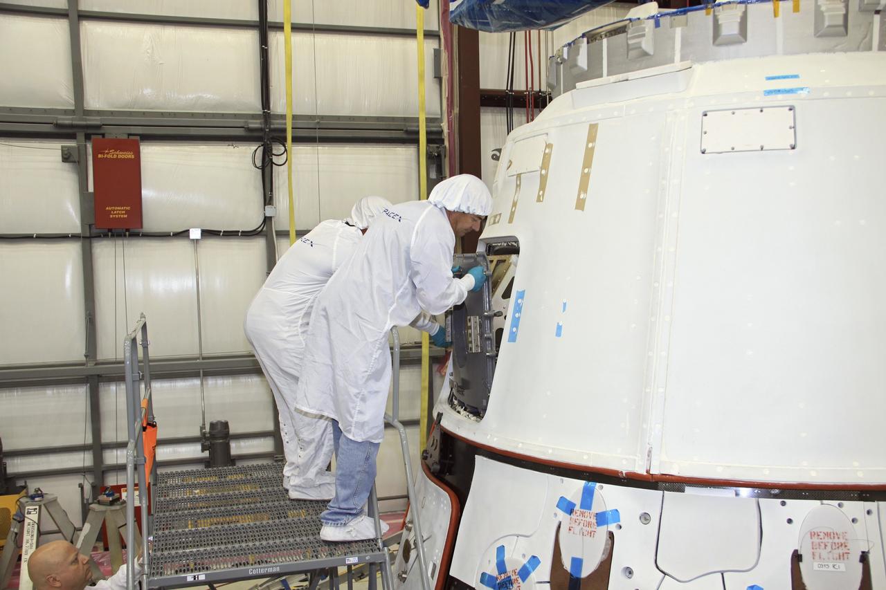 CAPE CANAVERAL, Fla. – In a processing hangar at Space Launch Complex-40 on Cape Canaveral Air Force Station in Florida, Space Exploration Technologies technicians close the hatch of the Dragon capsule.  The hatch was open for cargo to be stowed in the capsule in preparation for its scheduled April 30 liftoff aboard a Falcon 9 rocket.    Known as SpaceX, the launch will be the company's second demonstration test flight for NASA's Commercial Orbital Transportation Services program, or COTS. During the flight, the capsule will conduct a series of checkout procedures to test and prove its systems, including rendezvous and berthing with the International Space Station. The cargo includes food and provisions for the station’s Expedition crews, such as clothing, batteries, and computer equipment. Under COTS, NASA has partnered with two private companies to launch cargo safely to the station. For more information, visit http://www.nasa.gov/spacex.  Photo credit: NASA/Jim Grossmann