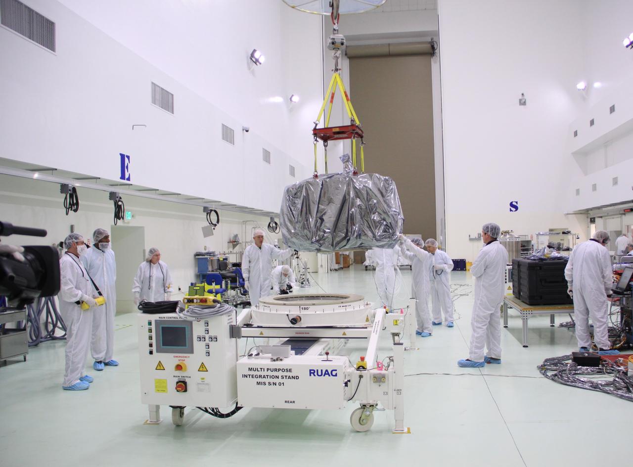 CAPE CANAVERAL, Fla. – In the clean room high bay at the Astrotech payload processing facility near NASA’s Kennedy Space Center in Florida, Applied Physics Laboratory technicians lift NASA's Radiation Belt Storm Probe A, wrapped in a protective shroud, onto a test stand. Prelaunch preparations and spacecraft testing will follow.      The Radiation Belt Storm Probes, or RBSP, mission will help us understand the sun’s influence on Earth and near-Earth space by studying the Earth’s radiation belts on various scales of space and time. RBSP instruments will provide the measurements needed to characterize and quantify the plasma processes that produce very energetic ions and relativistic electrons. The mission is part of NASA’s broader Living With a Star Program that was conceived to explore fundamental processes that operate throughout the solar system, particularly those that generate hazardous space weather effects in the vicinity of Earth and phenomena that could impact solar system exploration. RBSP will begin its mission of exploration of Earth's Van Allen radiation belts and the extremes of space weather after launch. Launch aboard a United Launch Alliance Atlas V rocket is scheduled for August 23. For more information, visit http://www.nasa.gov/rbsp. Photo credit: NASA/Jim Grossmann